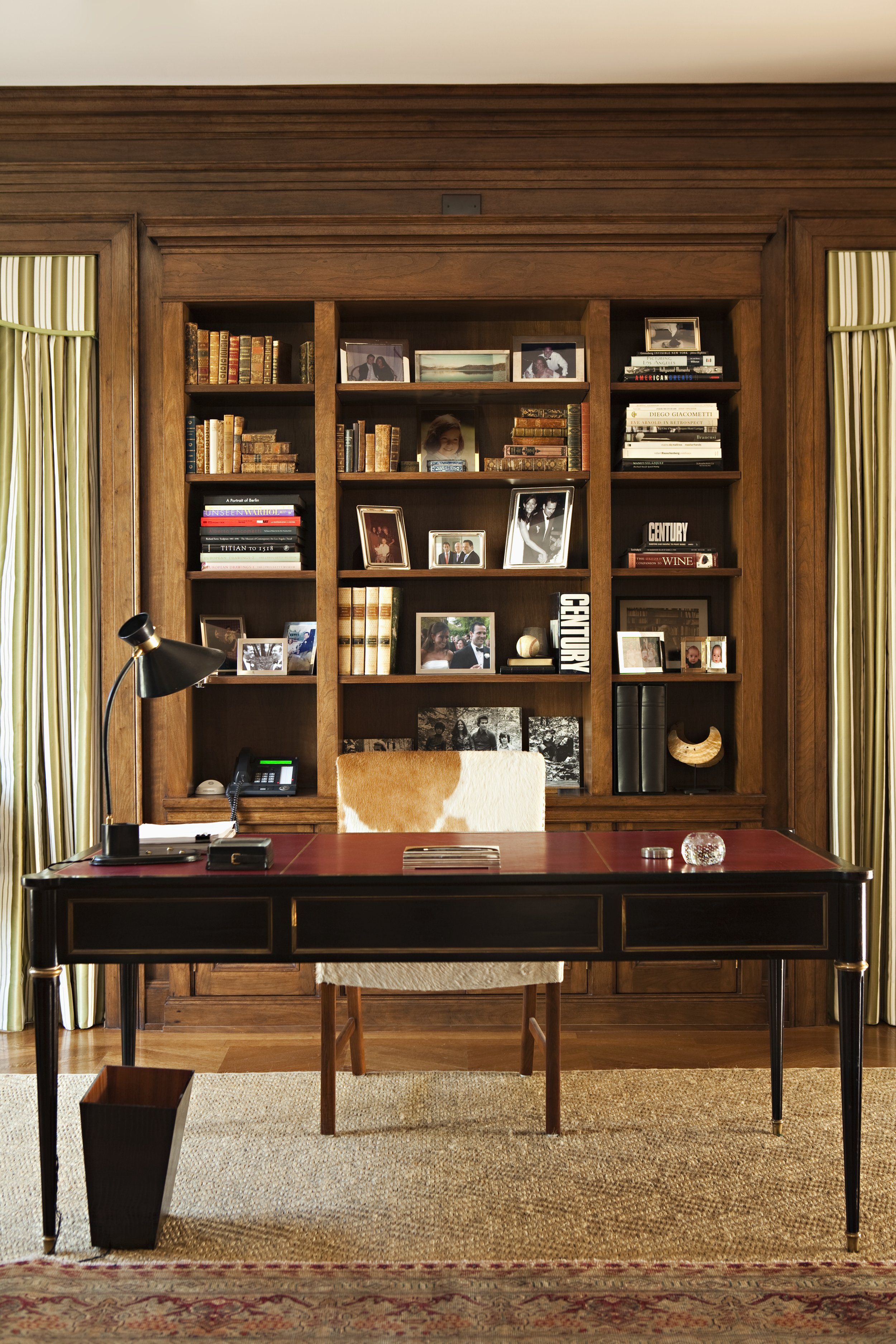 Study with a mahogany desk, built-in bookshelves and framed photographs