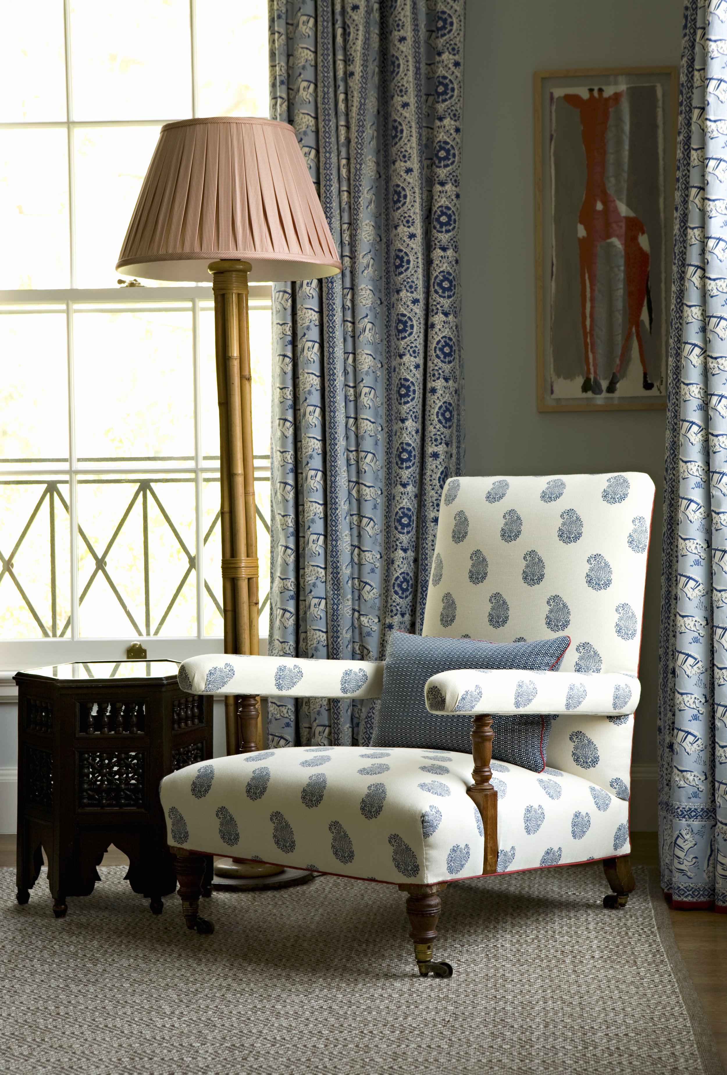 Armchair in blue paisley fabric with blue floral drapes and a bamboo mirror
