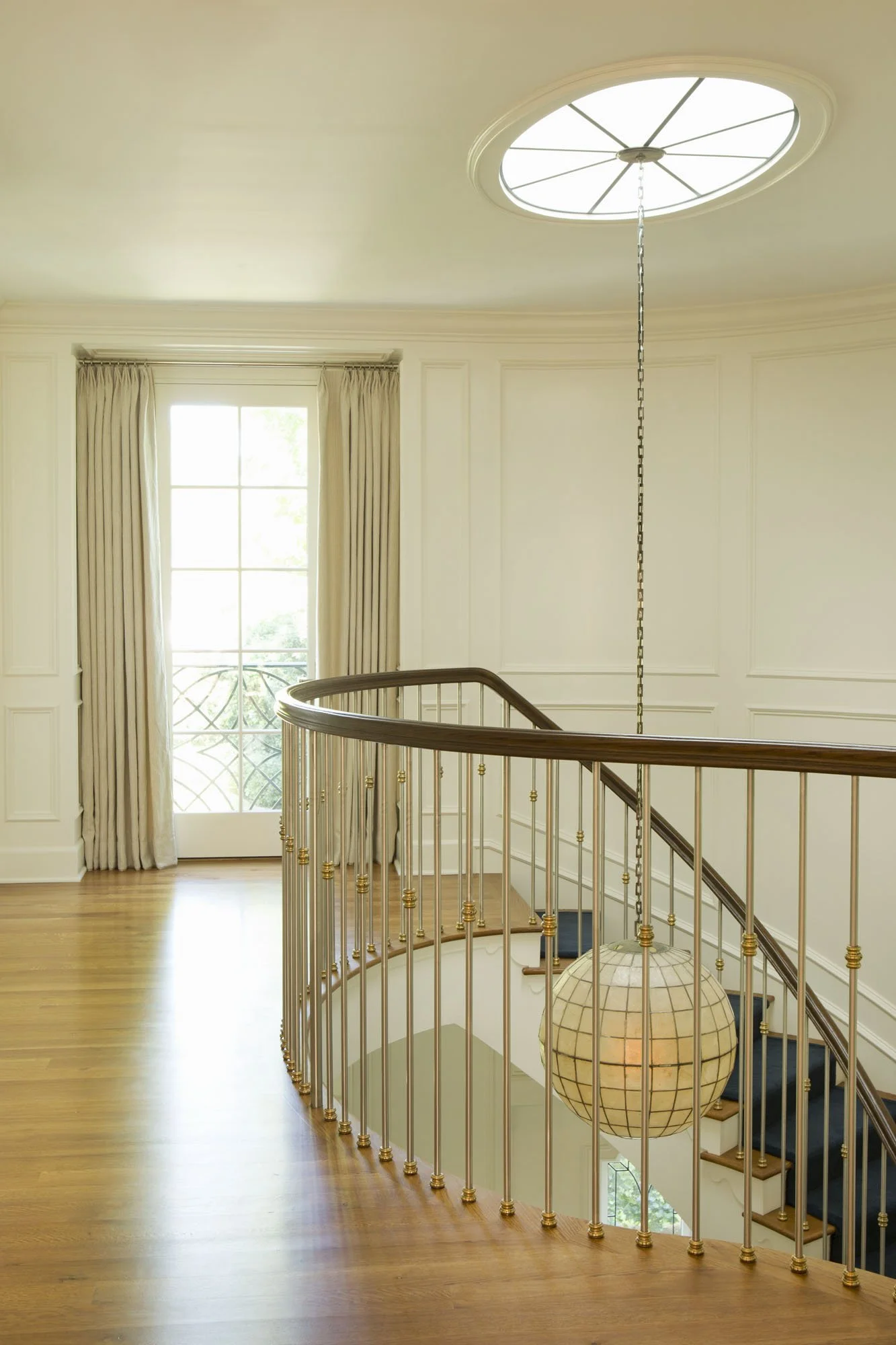 Curved stair landing with brass railing and paneled walls