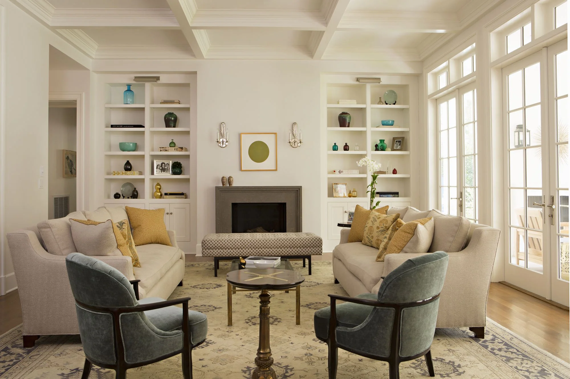 Living room with coffered ceiling, built-in shelves, fireplace and slate blue chairs