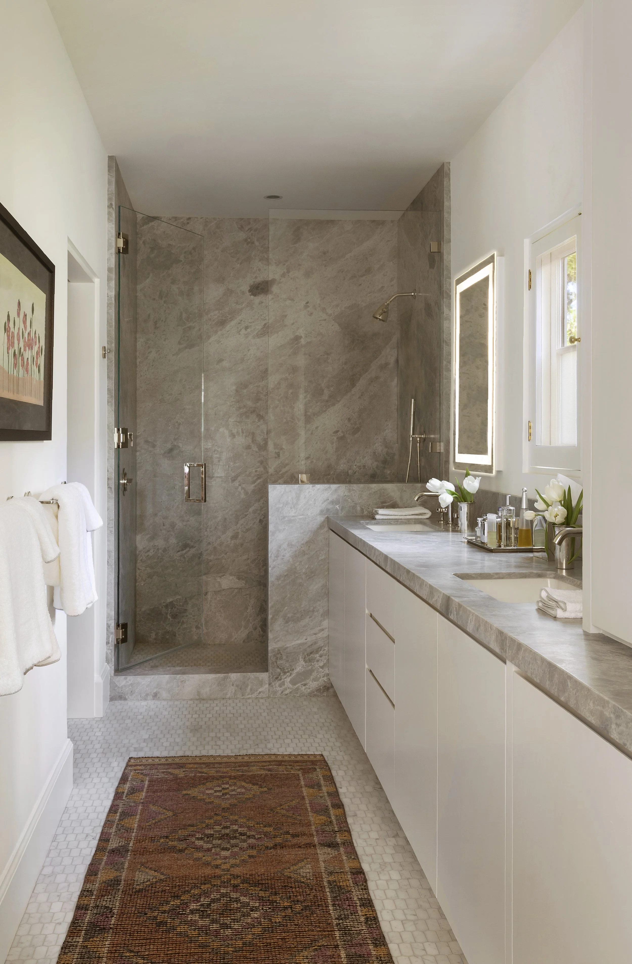 Bath with a stone shower, marble vanity and lighted mirror