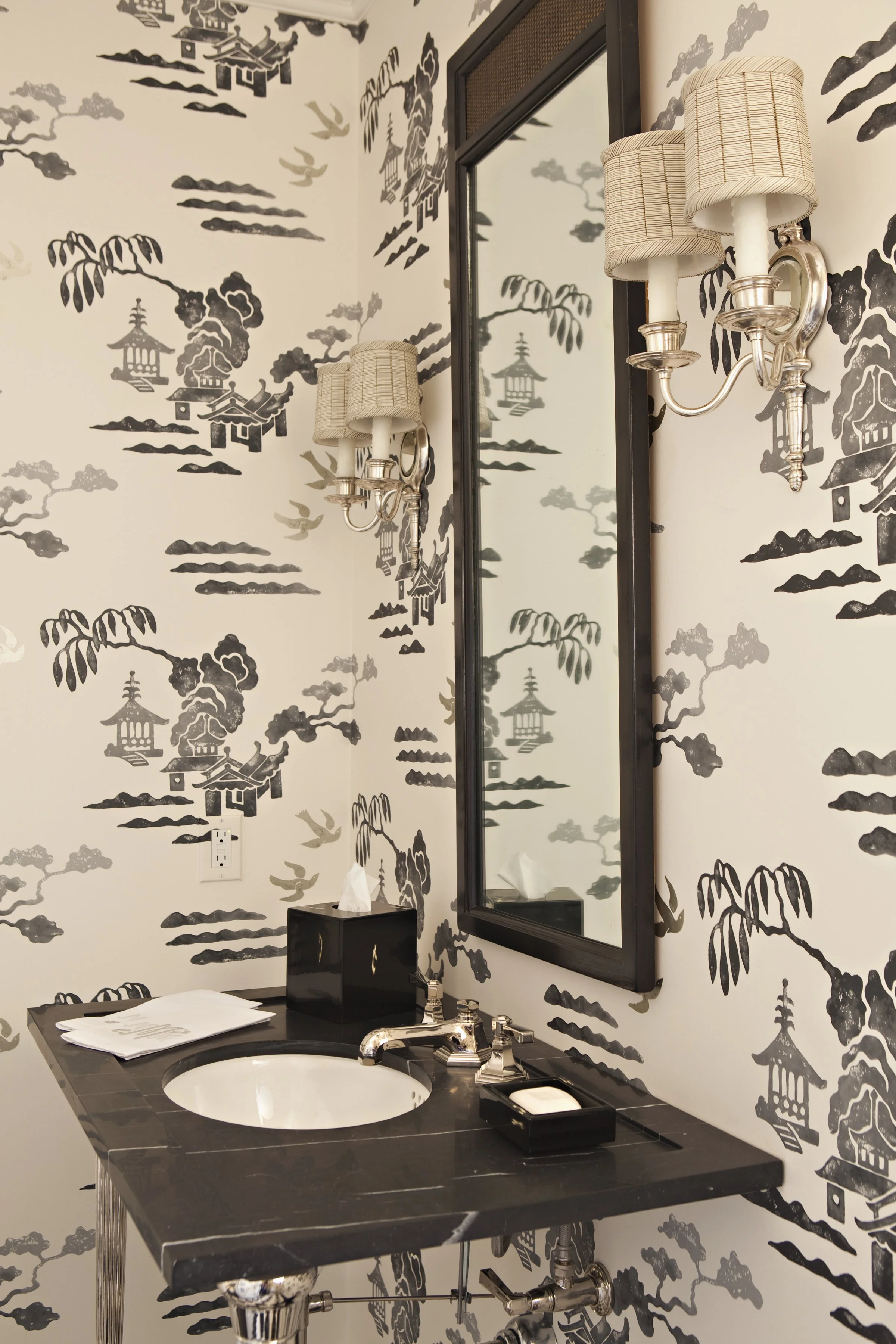 Black and white chinoiserie wallpaper with a dark framed mirror