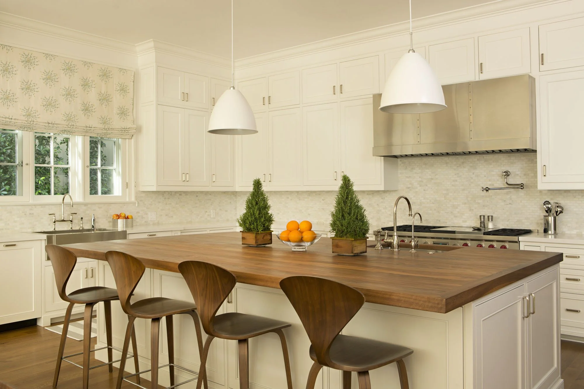 Kitchen with a walnut topped island, bentwood counter stools and white pendant lights