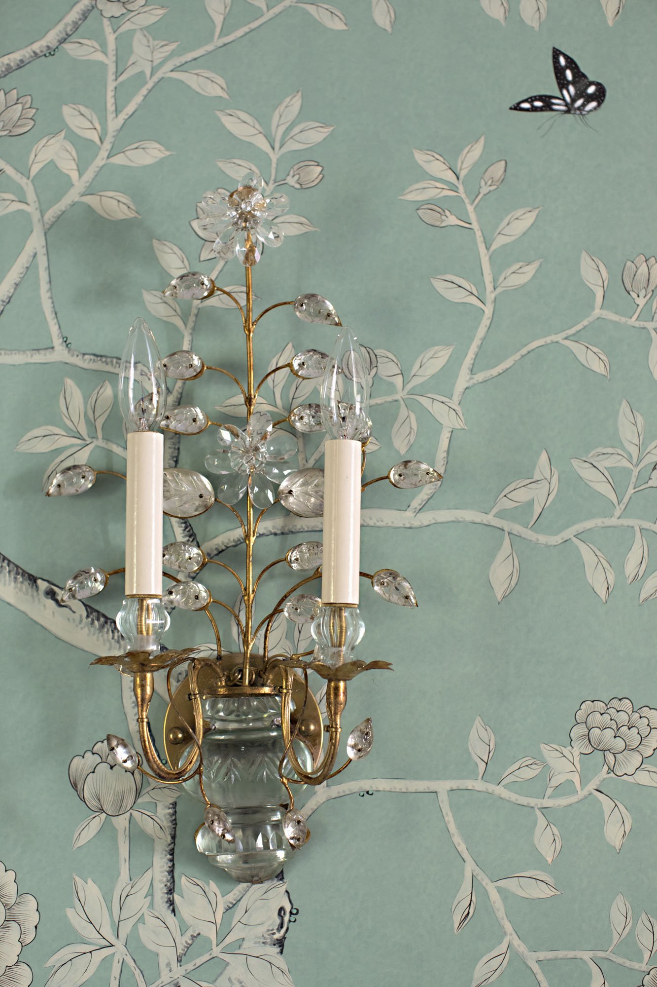 Crystal and brass sconce against celadon chinoiserie wallpaper