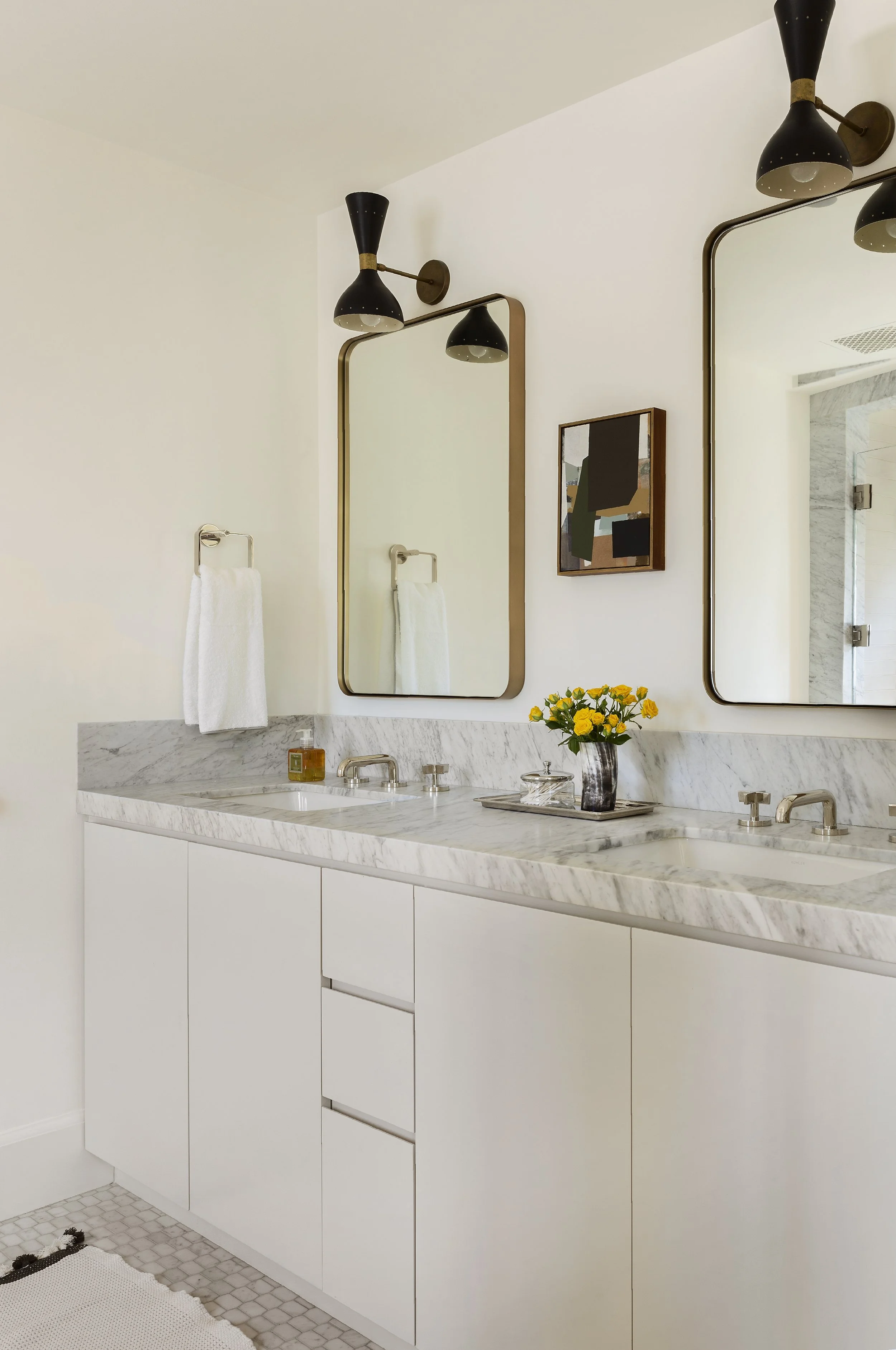 Marble double vanity with brass framed mirrors and yellow flowers