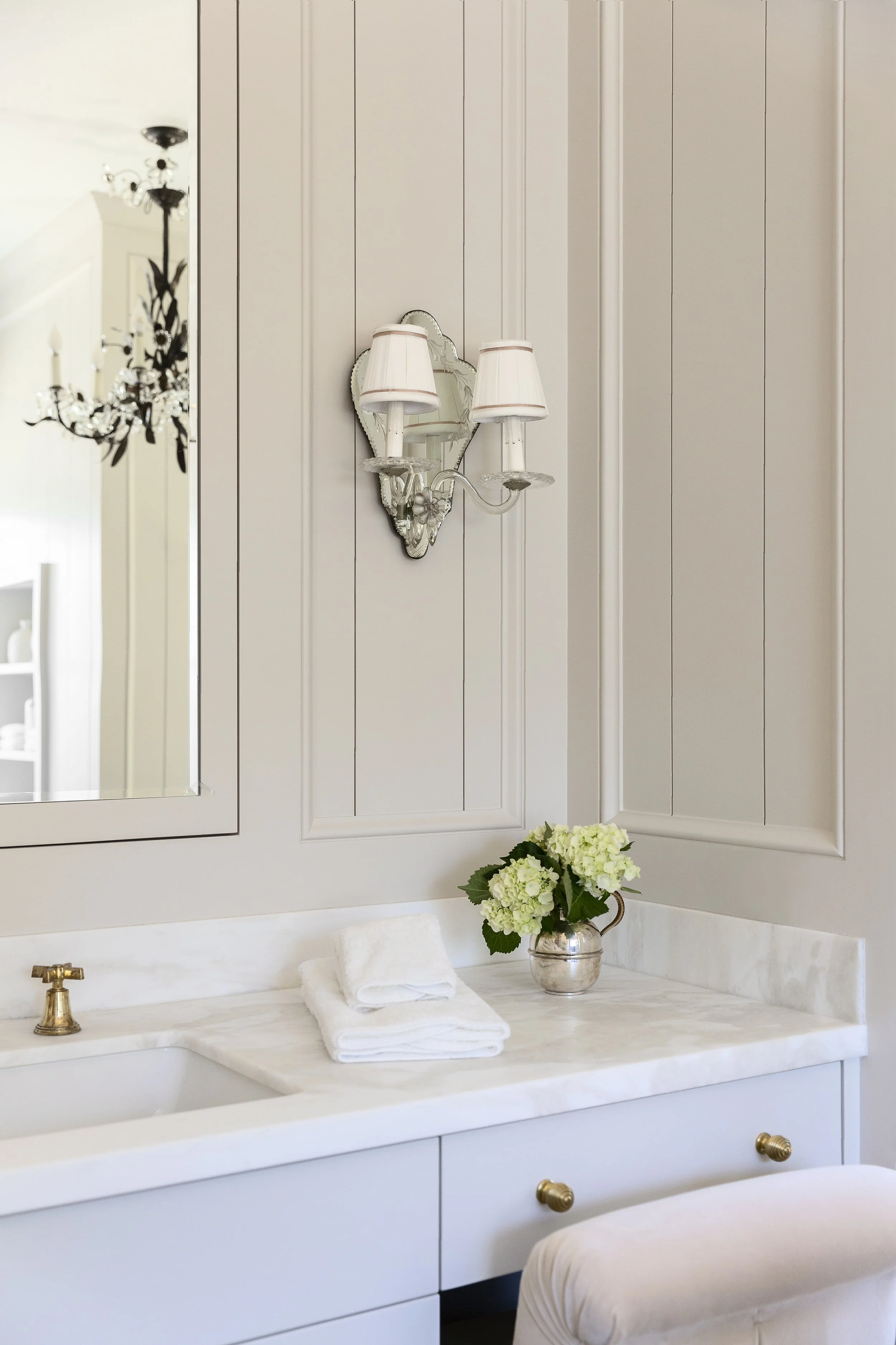 Bathroom wall with painted paneling, a sconce and green hydrangeas