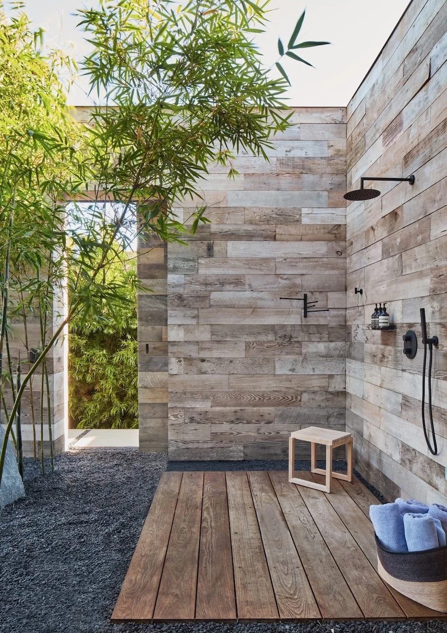 Outdoor shower enclosed in weathered reclaimed wood with bamboo and black fixtures
