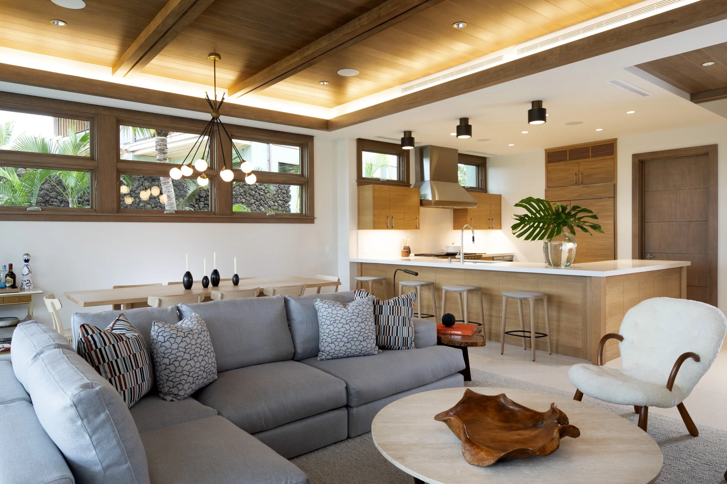 Open kitchen and living area with a wood beamed ceiling, gray sectional and oak cabinetry