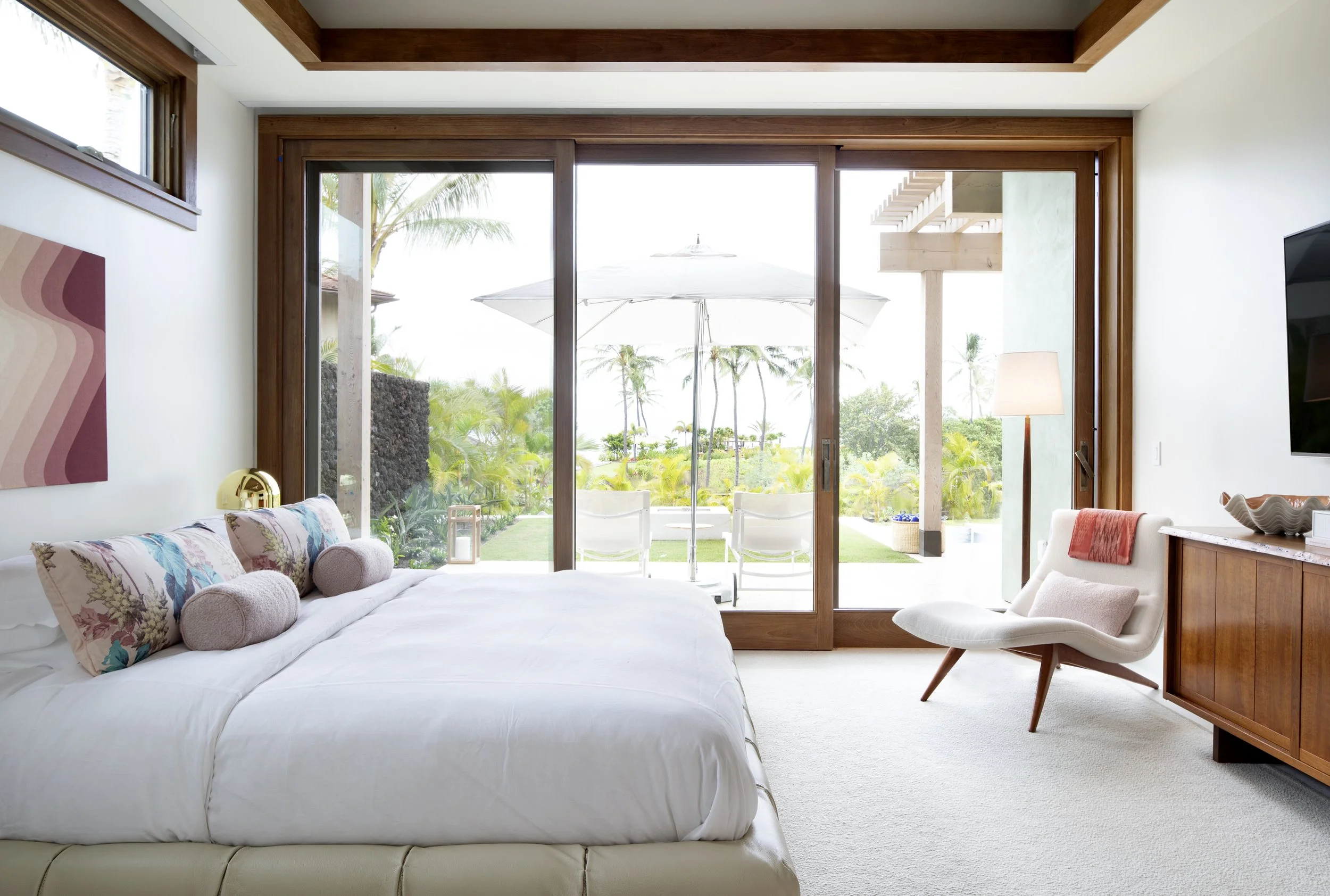 Primary bedroom with sliding doors opening to the pool and garden