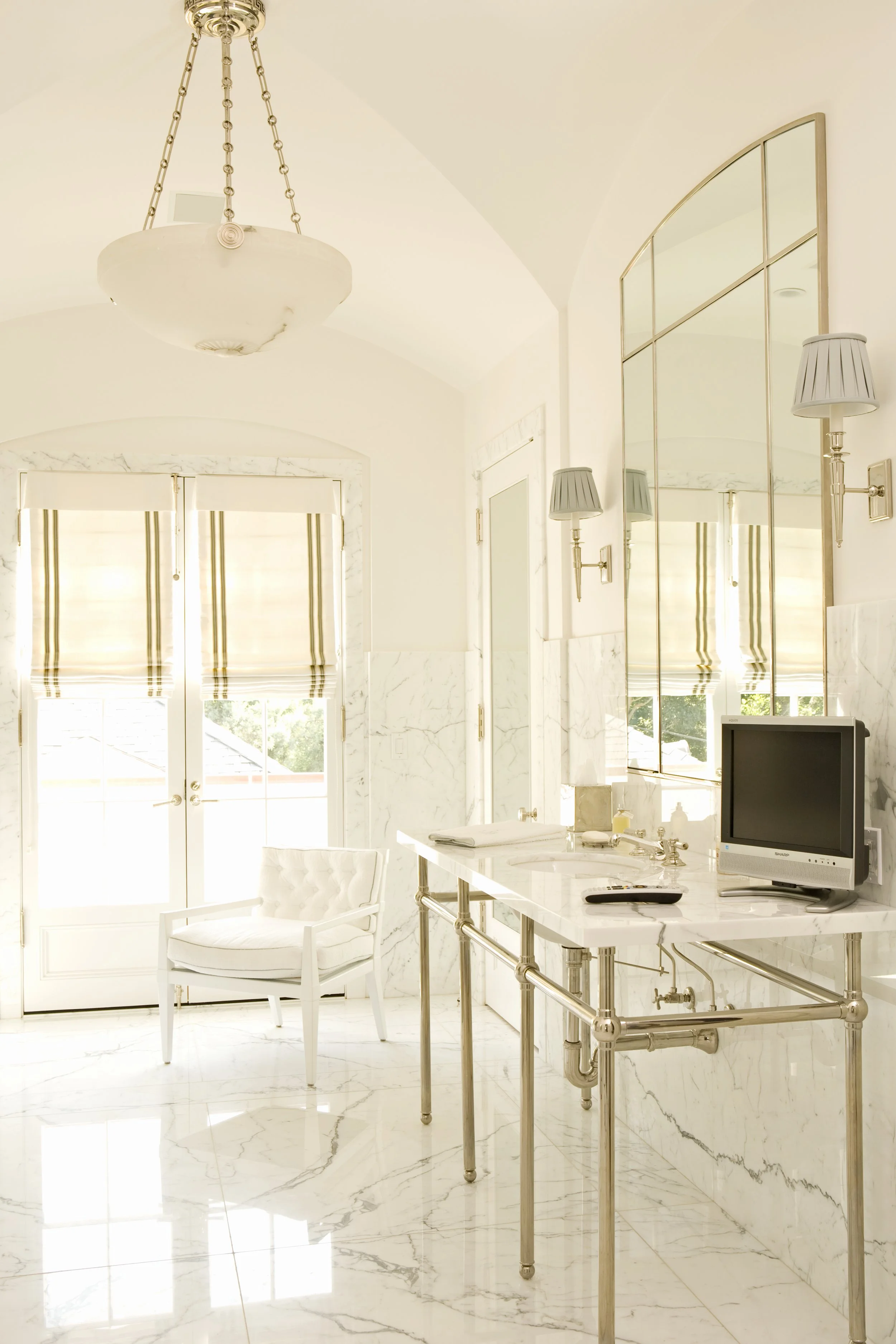 White dressing room with striped roman shades, a long desk and mirrored wall