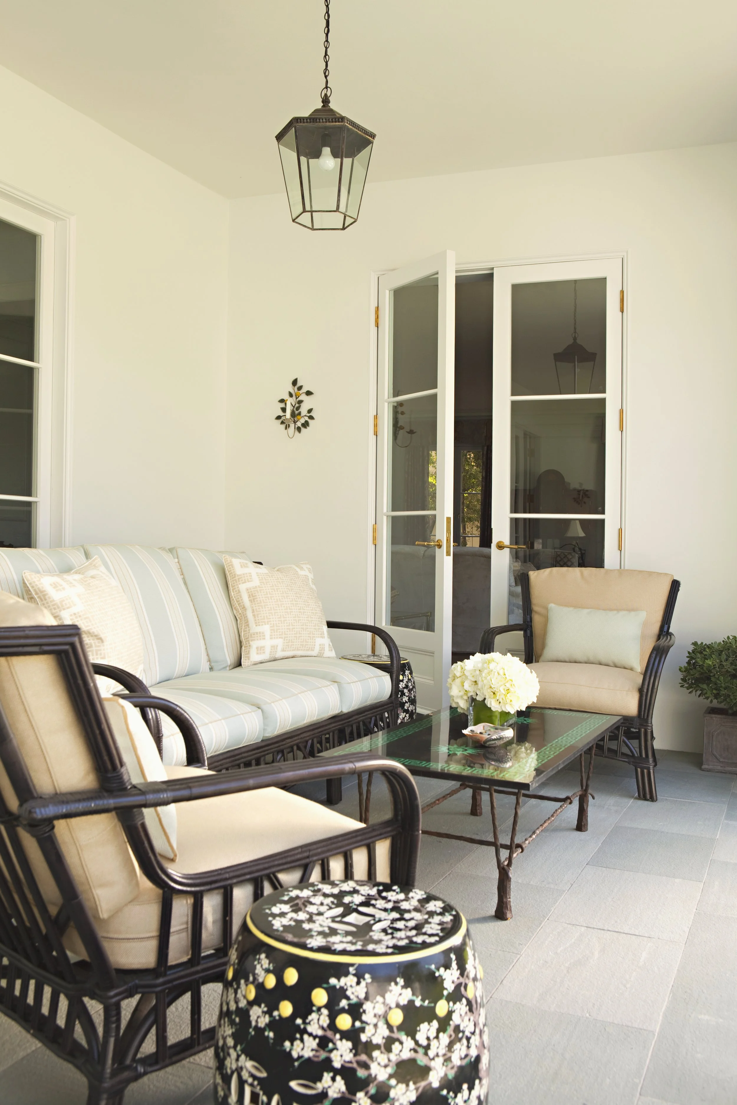Sunroom seating with a striped sofa, cream cushions and French doors
