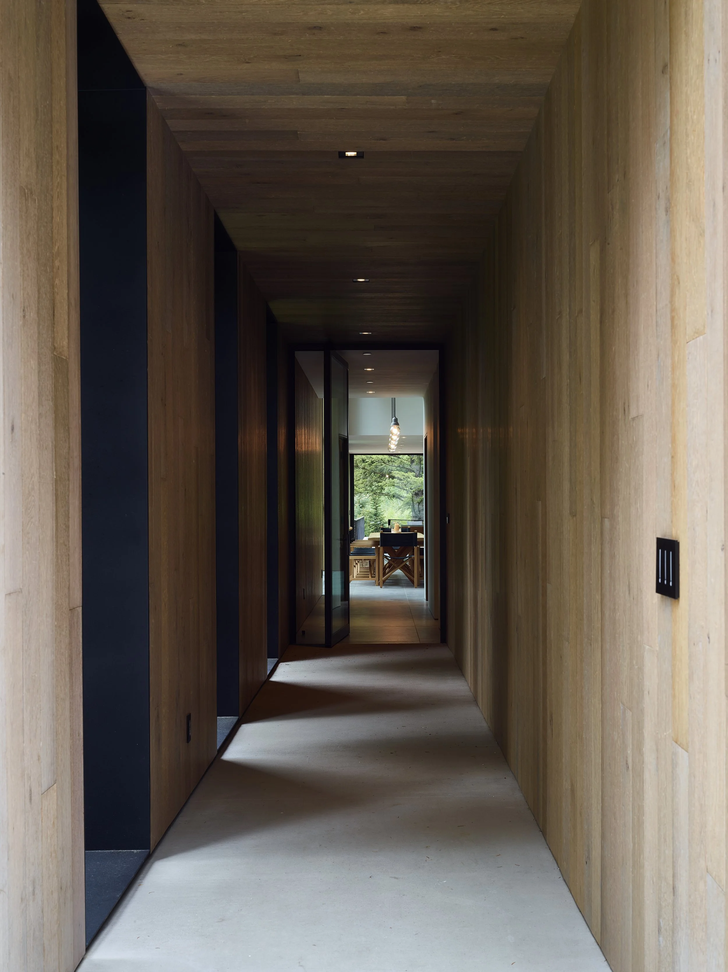 Narrow oak lined hallway leading toward the outdoors