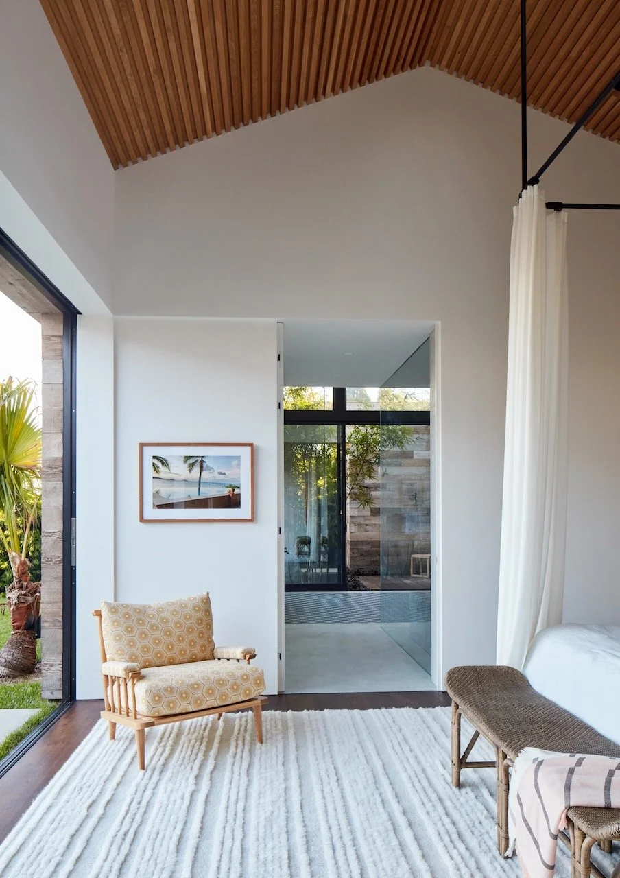 Entry hall with a framed beach photograph, white curtains and a glimpse of a reclaimed wood courtyard