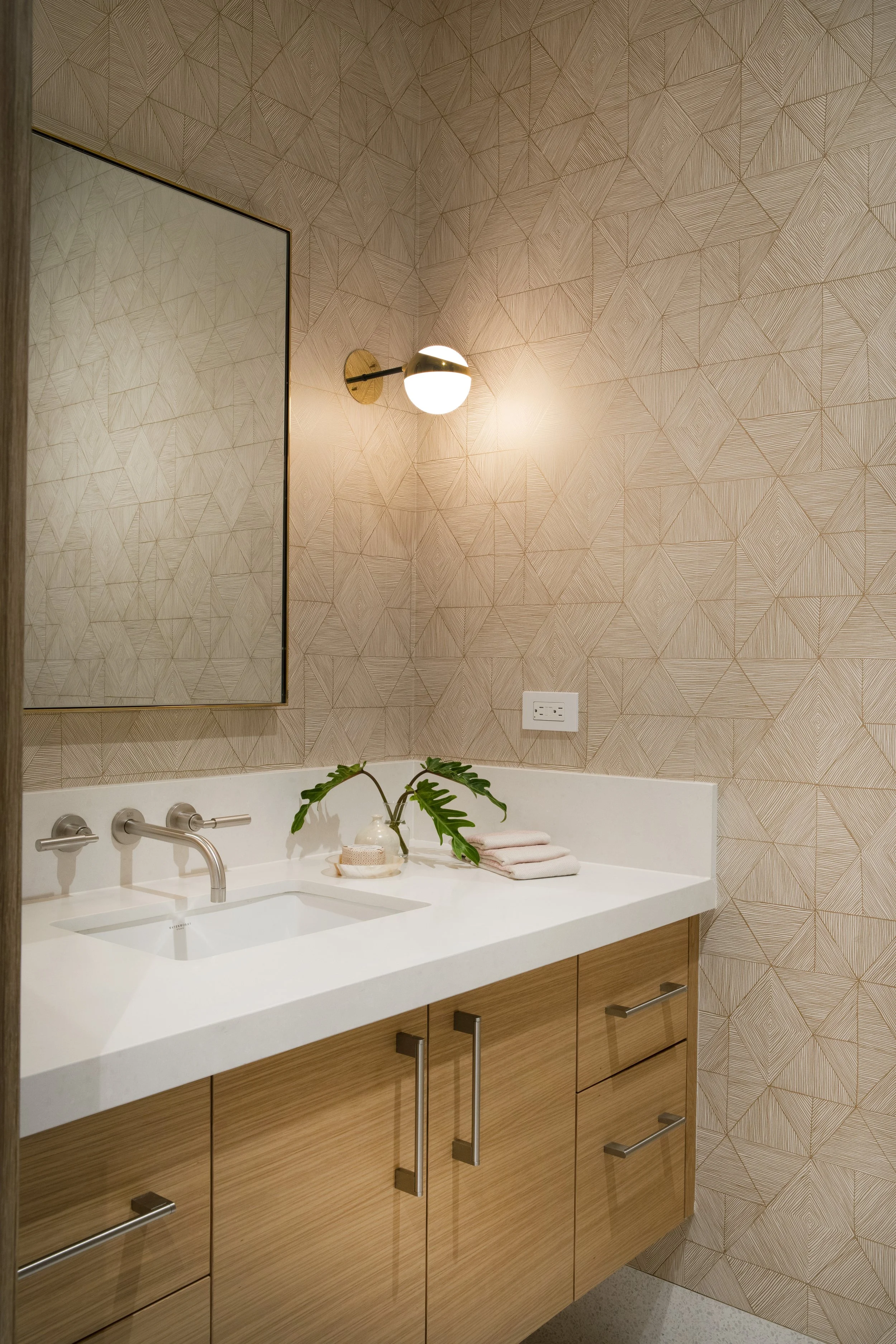 Powder room with a textured tile wall, white counter and brass wall faucet