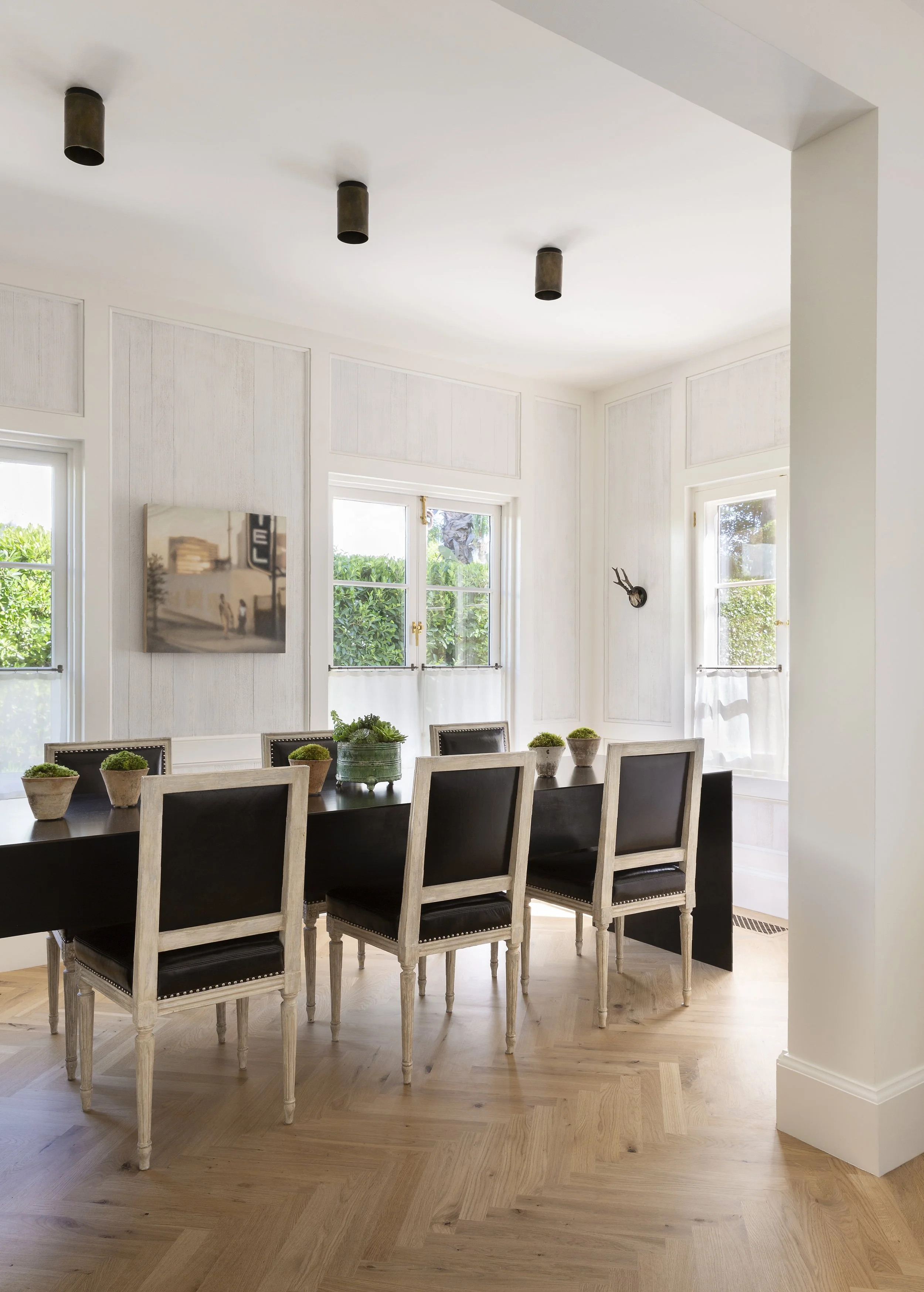 Dining room with a black table, black upholstered chairs and large windows to the garden