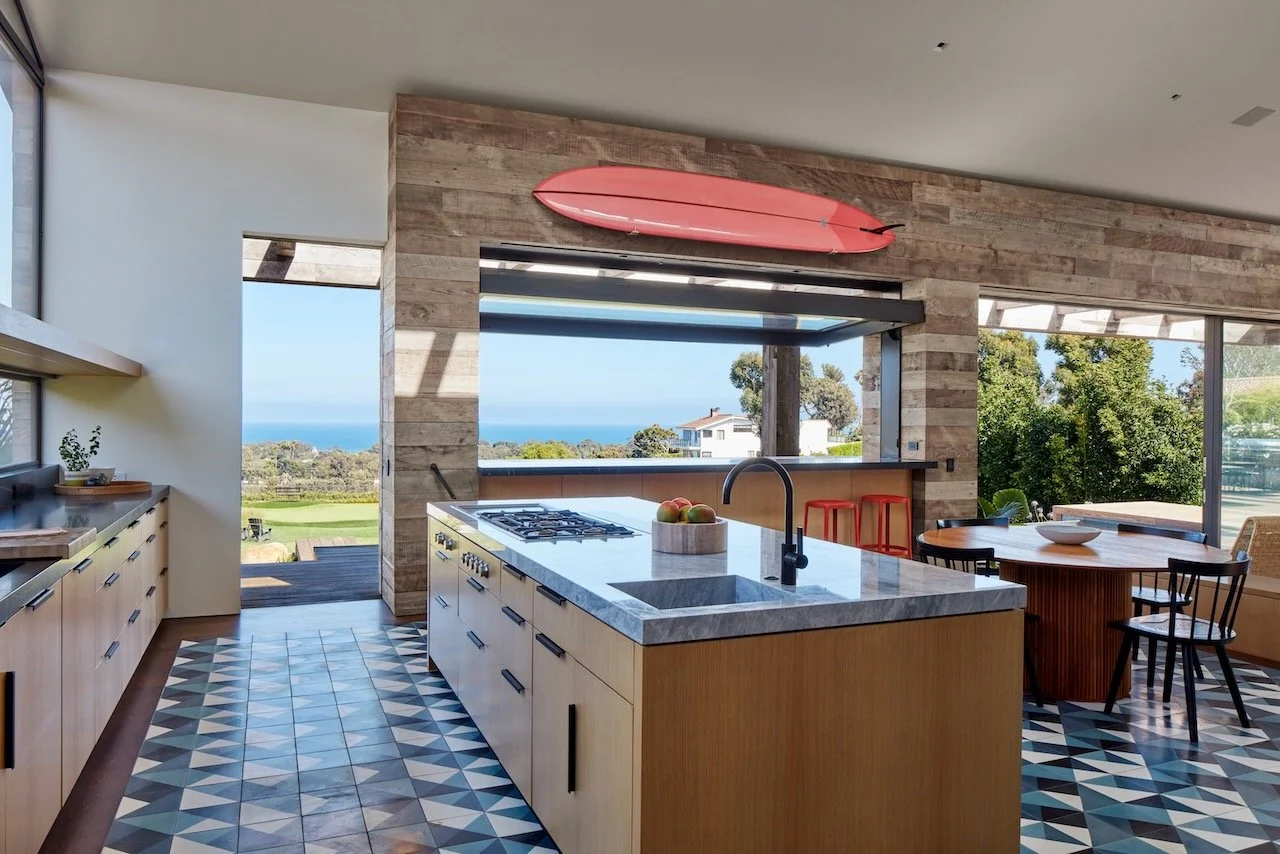 Kitchen island with stone top, blue geometric tile floor and an ocean view window