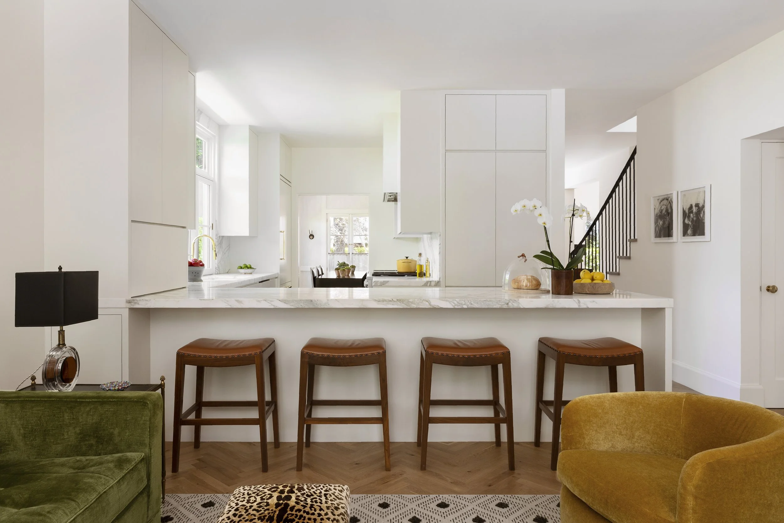 Kitchen with a marble counter, leather counter stools and a view into the living room
