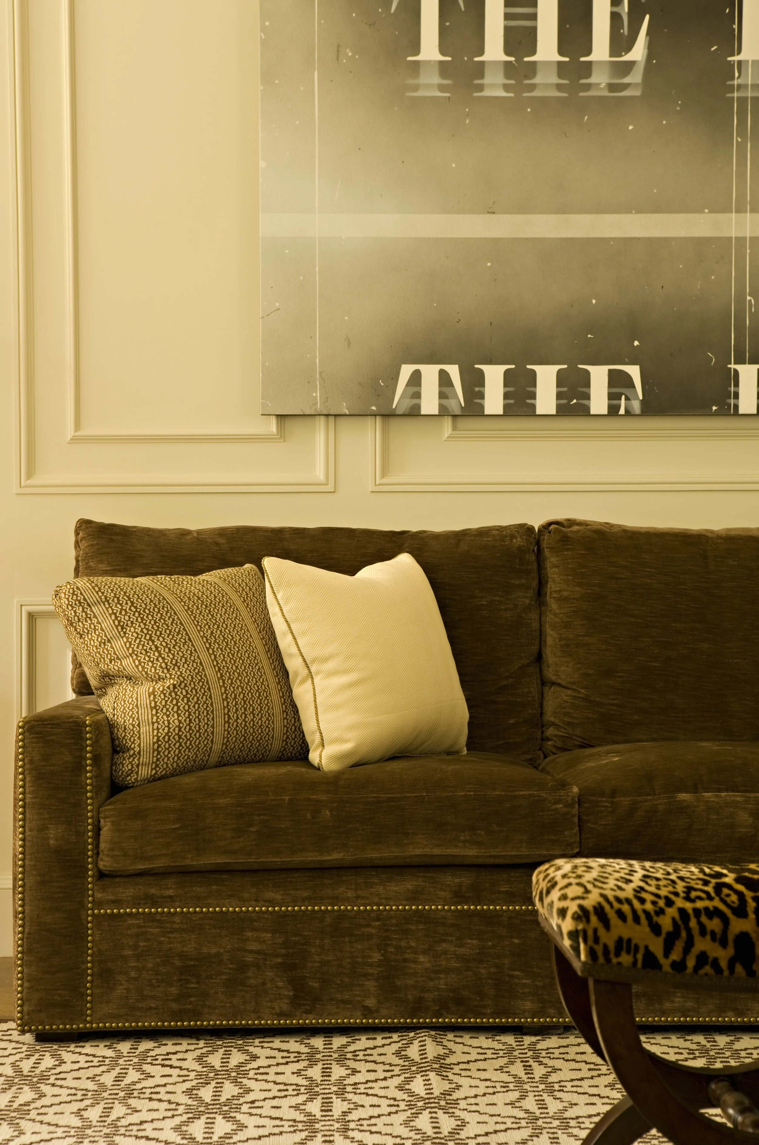 Brown velvet sofa with woven and cream pillows against a paneled wall