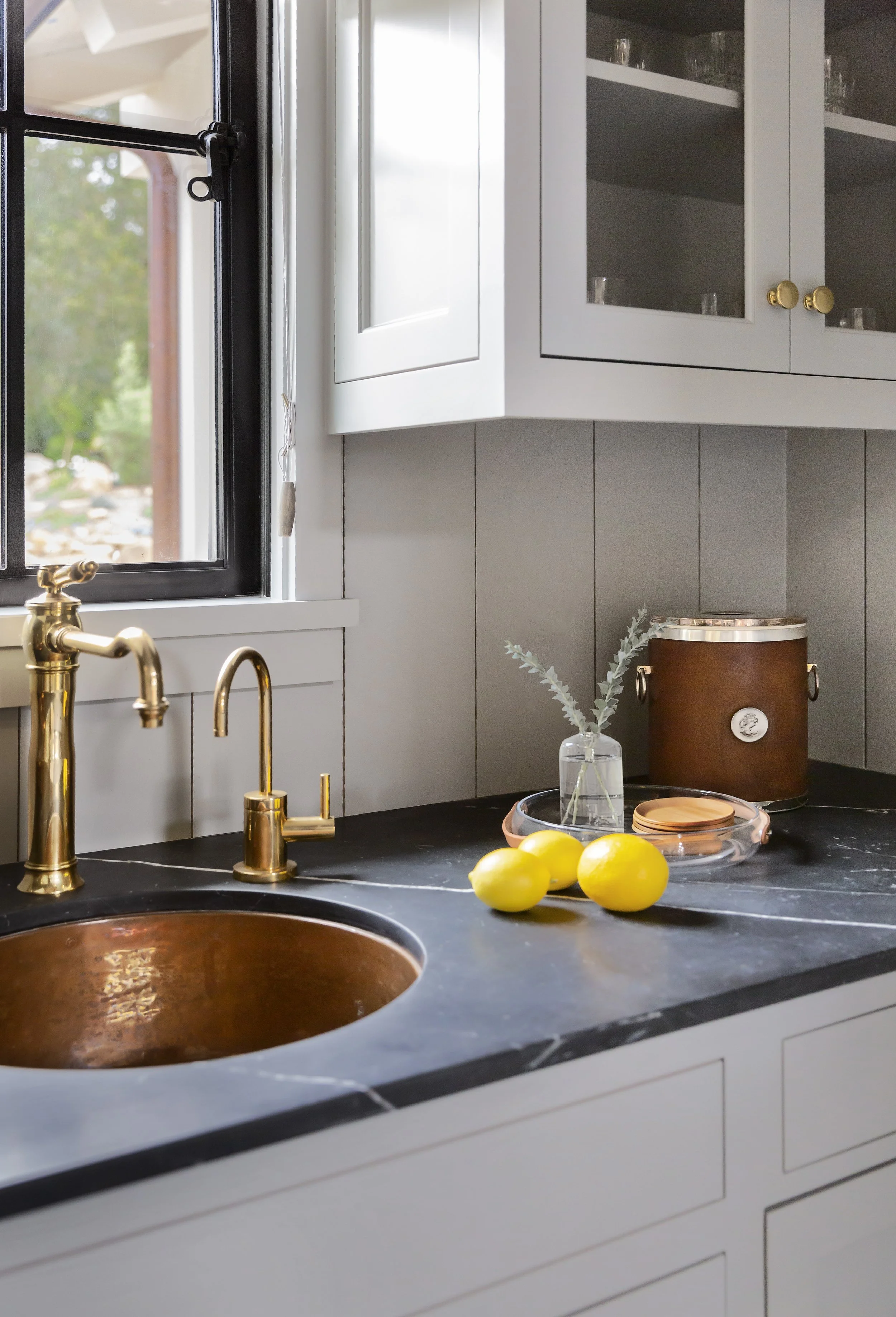 Brass faucets on a black stone counter with fresh lemons