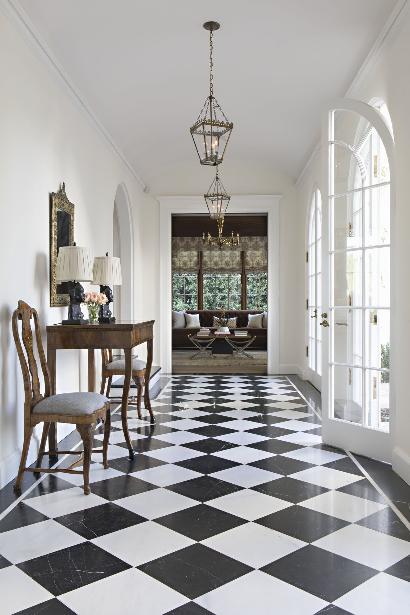 Entry hall with black and white checkerboard floor and French doors, with a view to the library
