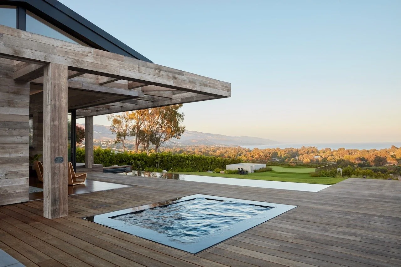 Plunge pool on a wood deck beneath a timber pergola, with distant hills and ocean beyond