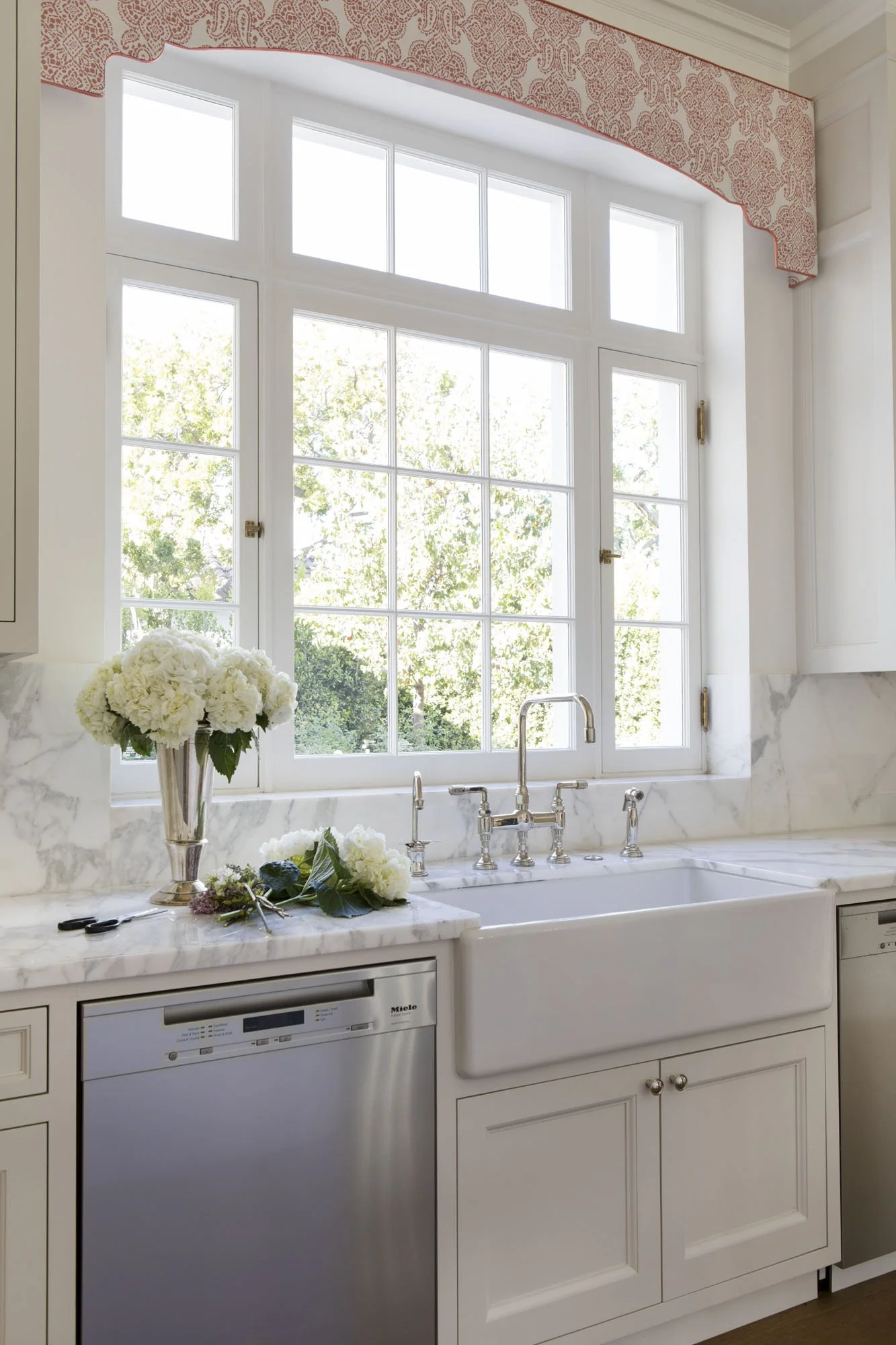 Farmhouse sink beneath a casement window with white hydrangeas