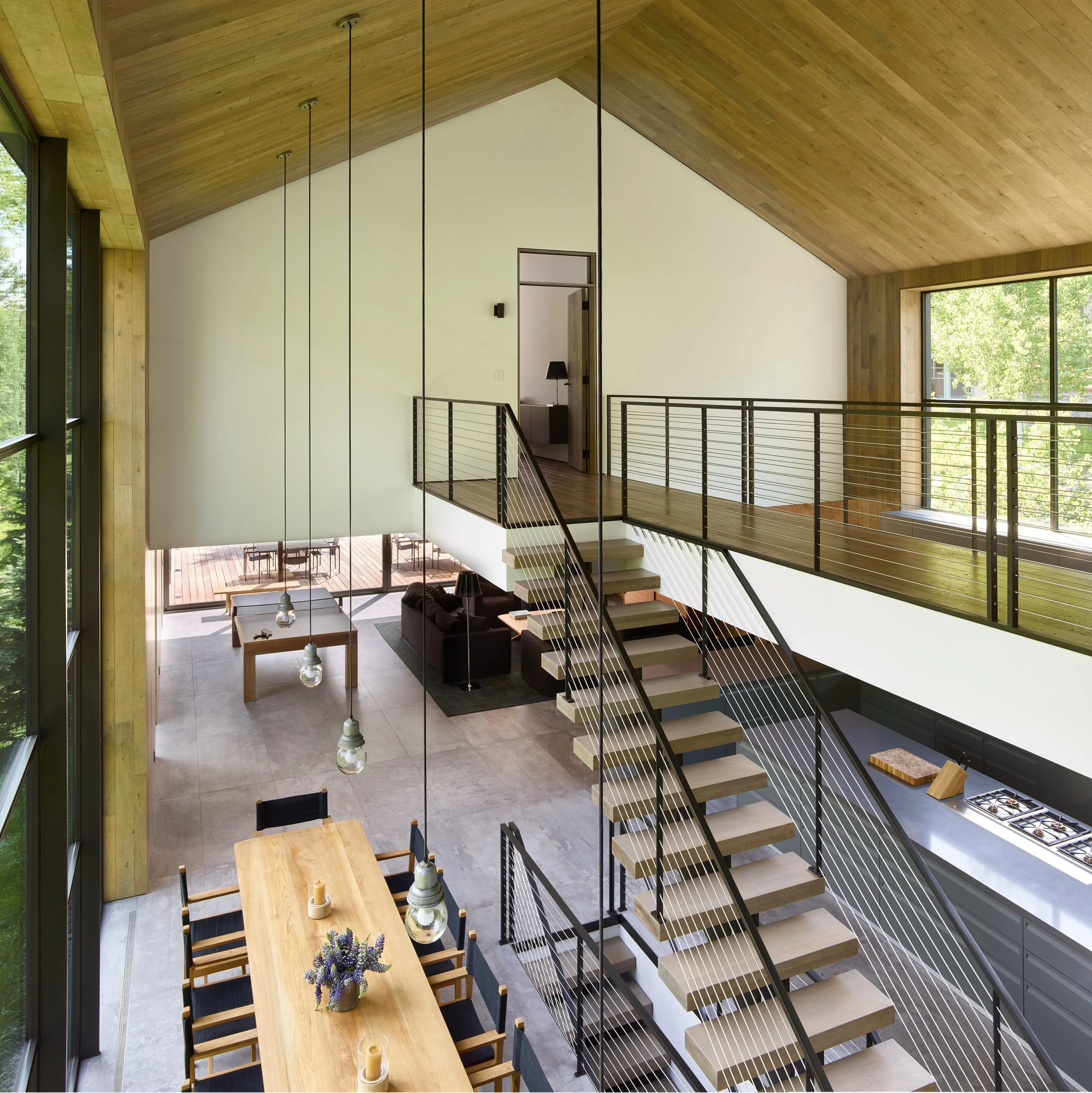 Mezzanine with a cable railing and floating stair above a sunken living area