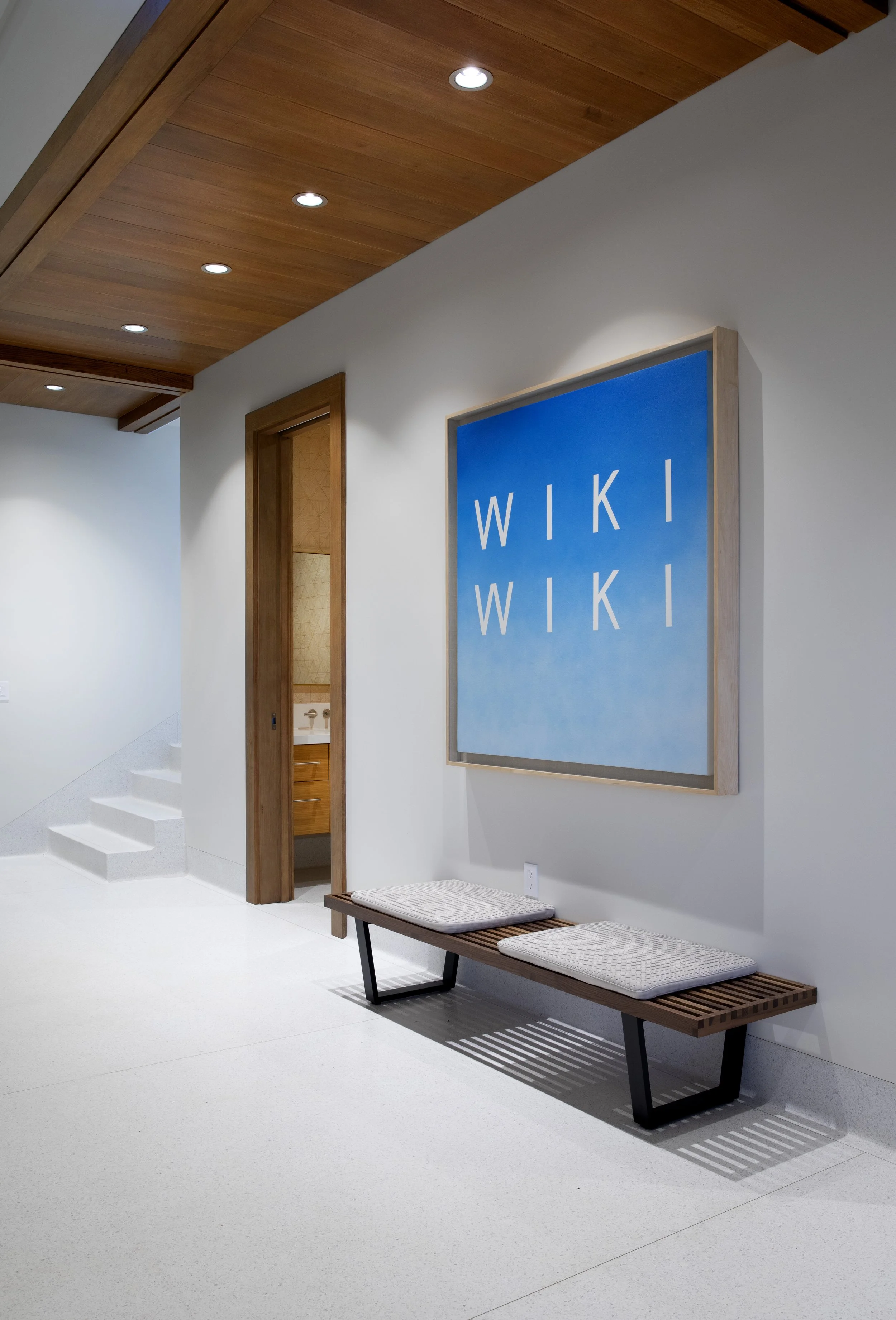 Stair landing with a blue graphic painting and a slatted bench