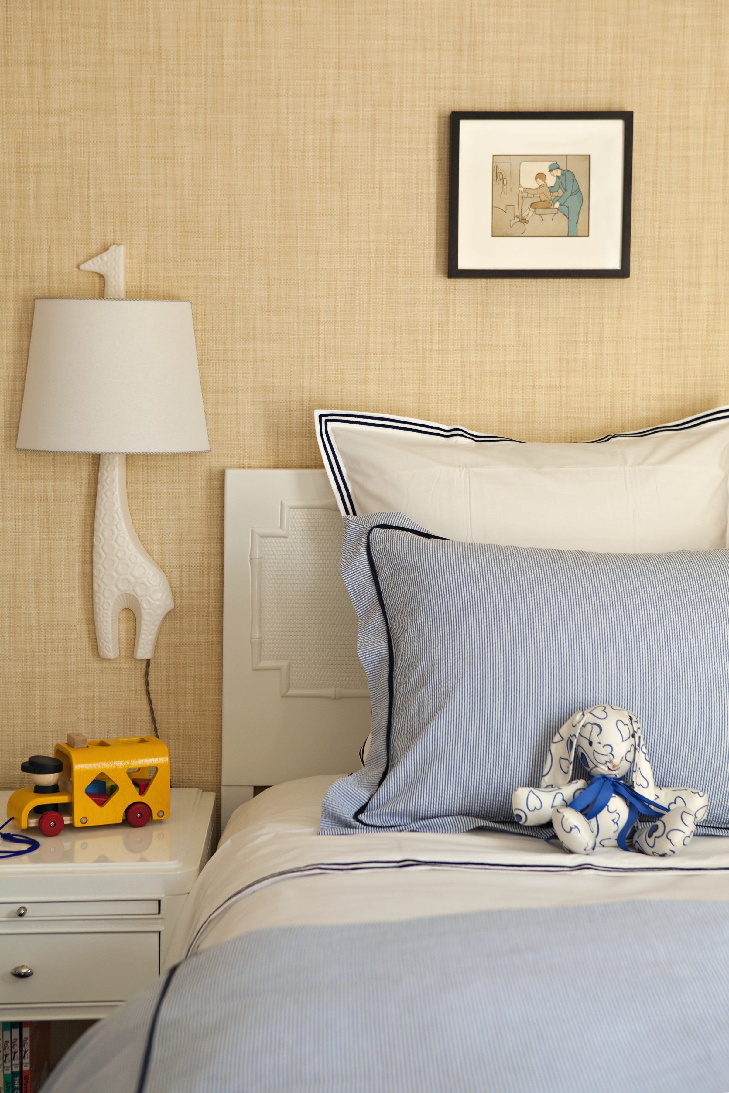 Giraffe wall lamp, blue pillows and a grasscloth wall in a child's room