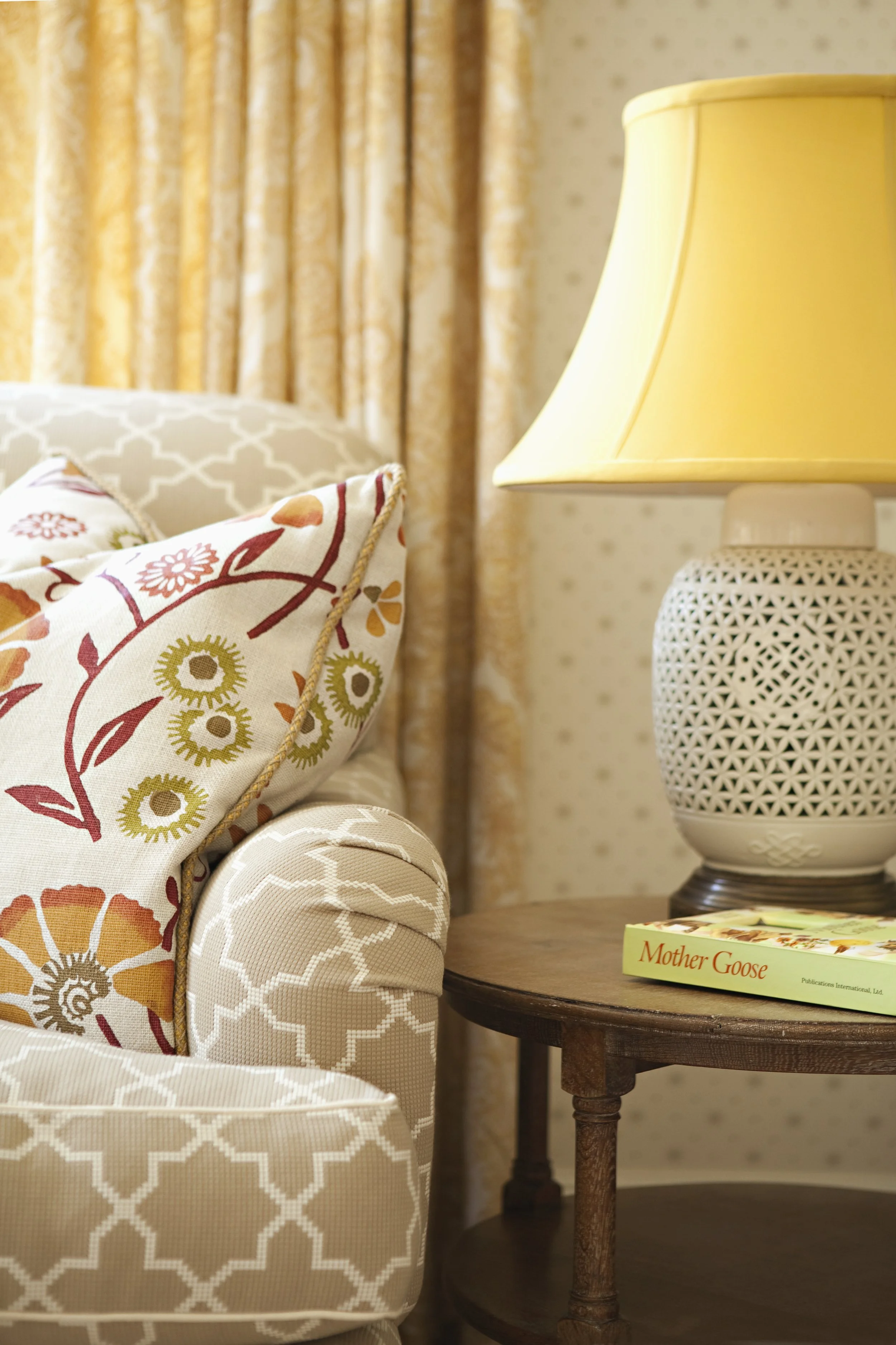 Detail of a floral pillow, pierced white lamp and quatrefoil wallpaper