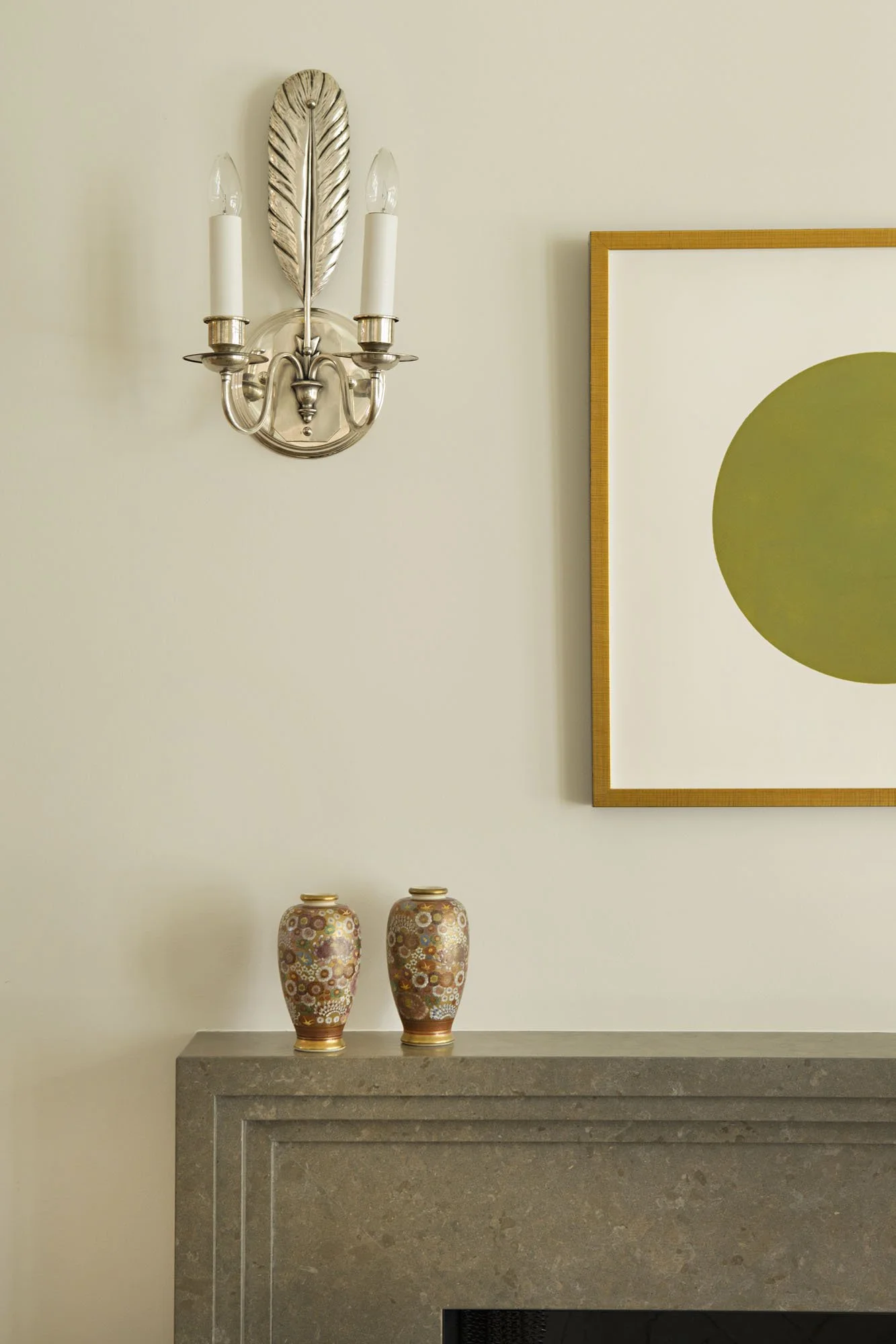 Silver sconce, framed abstract art with an olive circle and a pair of painted vases