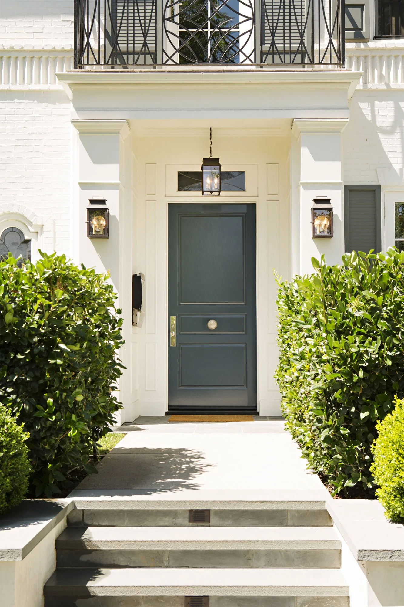 Front entry with a deep slate blue door, lanterns and clipped boxwood
