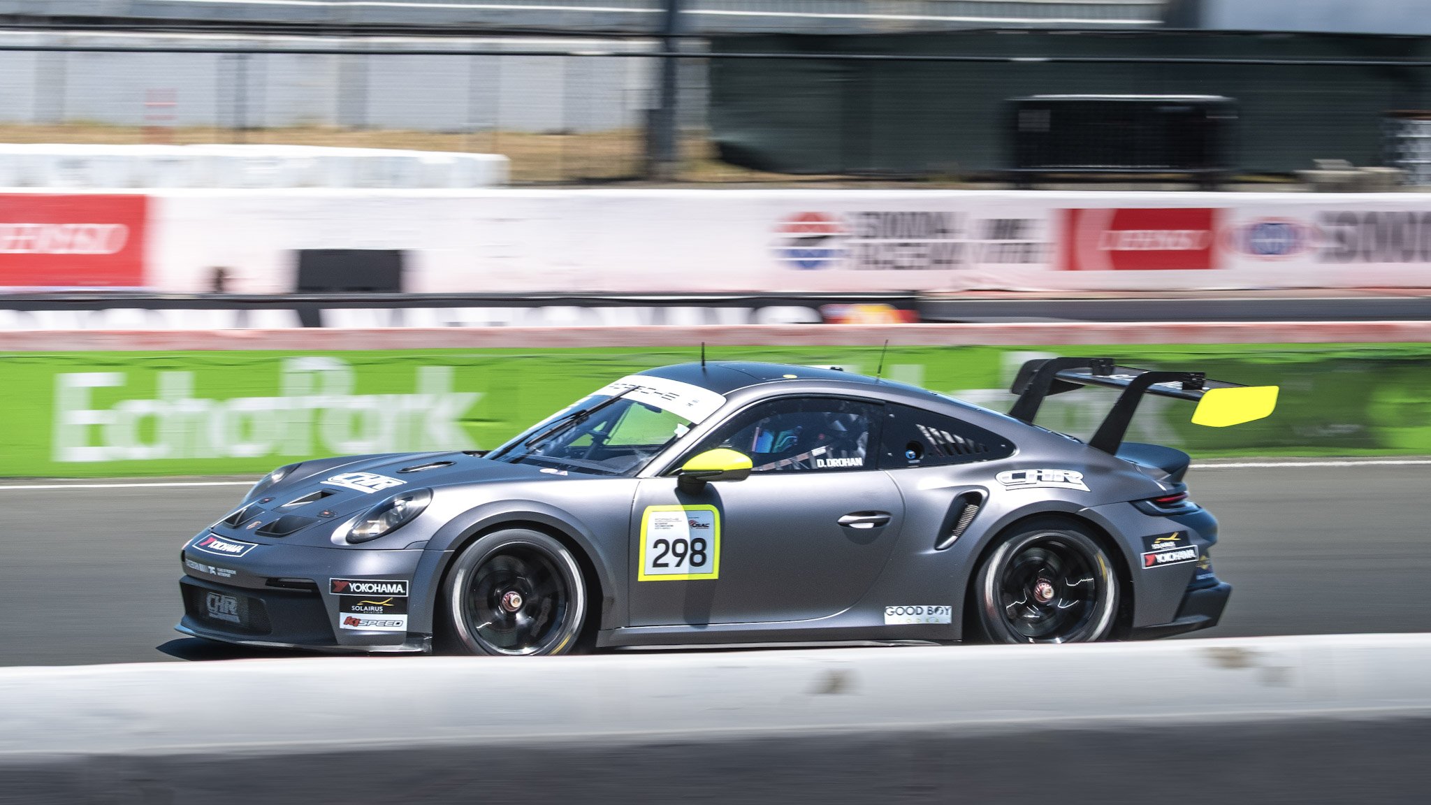 A racing car on a track, marked with the number 298, moving at high speed with a blurred background of advertising boards and barriers.