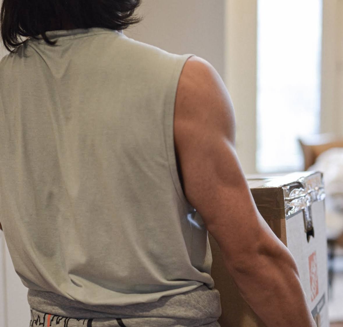 Mover carrying a cardboard moving box inside a home.