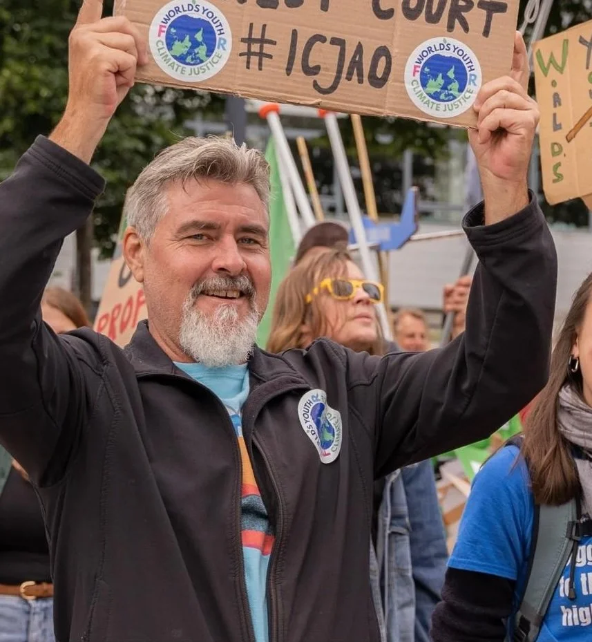 Justin Rose holding a World's Youth for Climate Justice #ICJAO placard at a climate action rally in Rotterdam