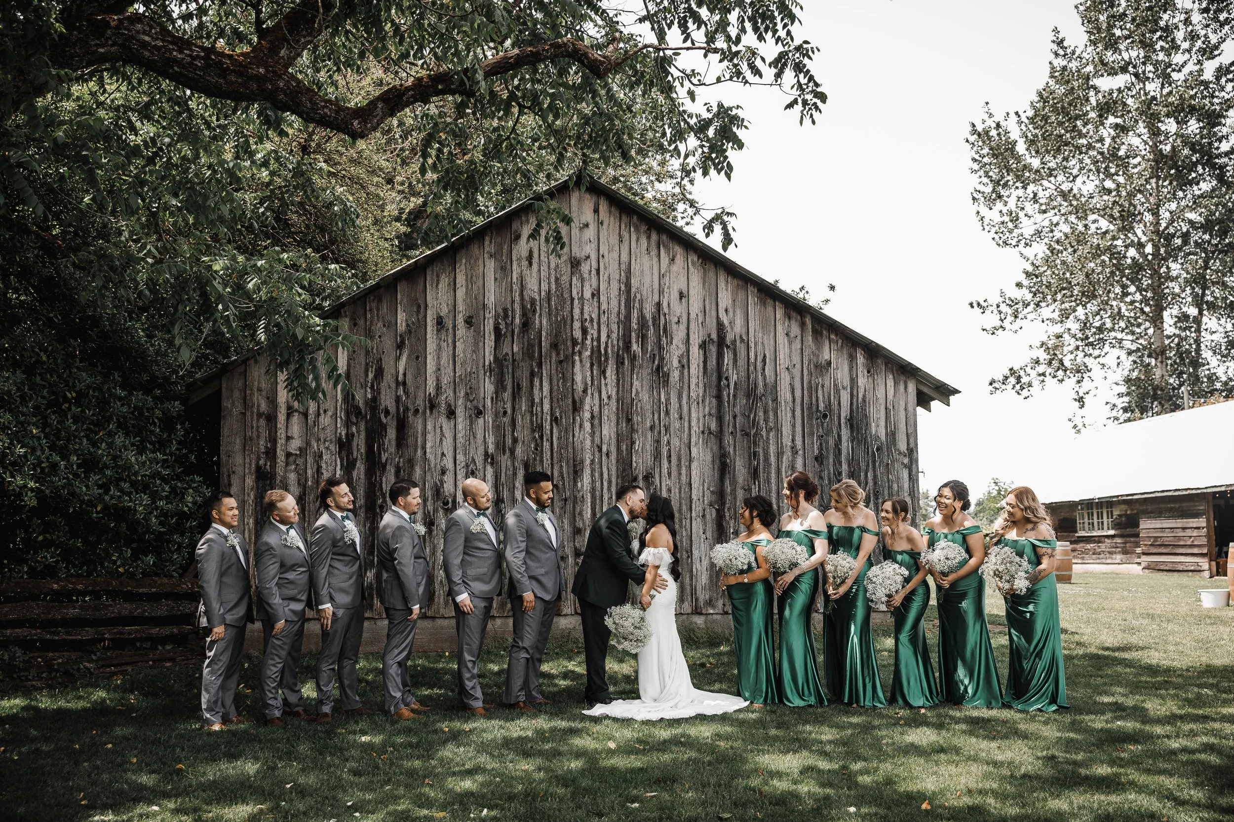 Bride, groom and wedding party posing beside a rustic wooden barn at Estate 248 in Aldergrove, photographed by Messmer Meadows Photography.