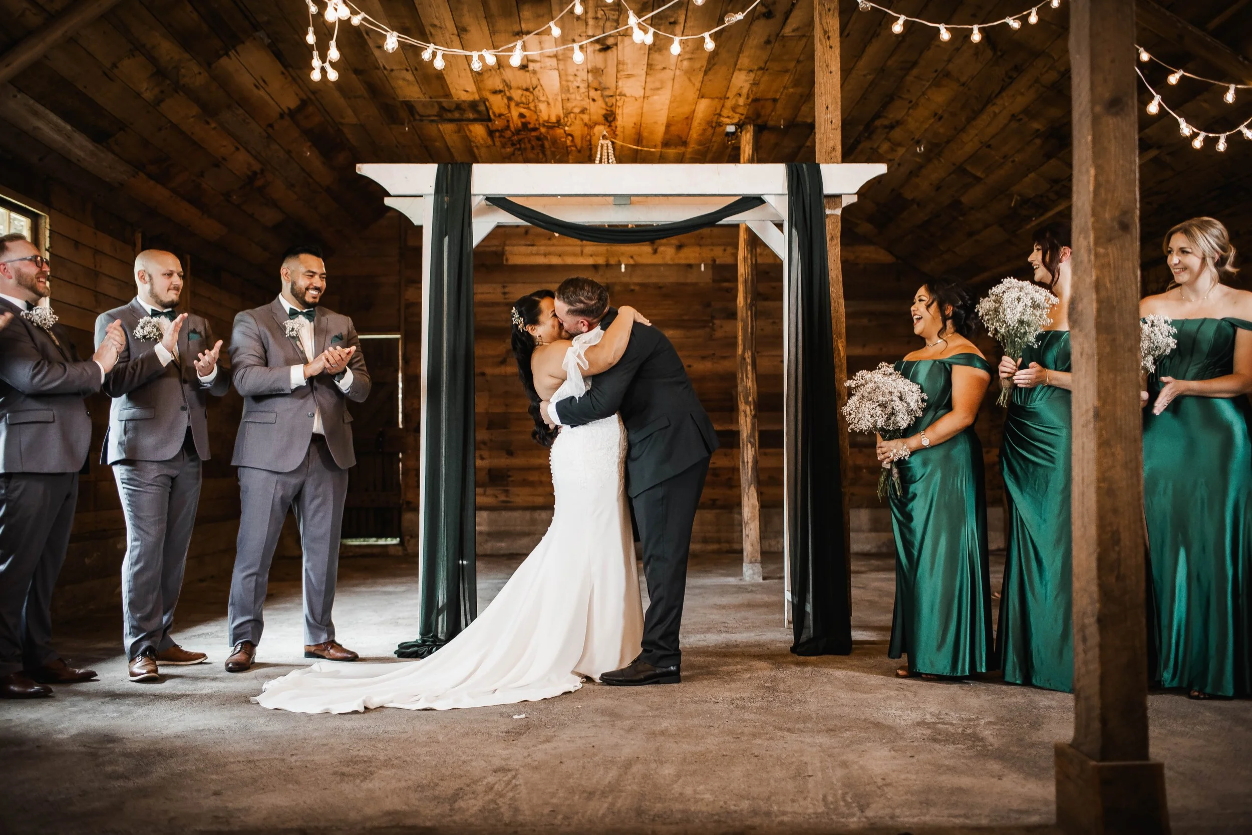 Bride and groom sharing their first kiss during an intimate indoor barn wedding ceremony at Estate 248 in Aldergrove, BC.