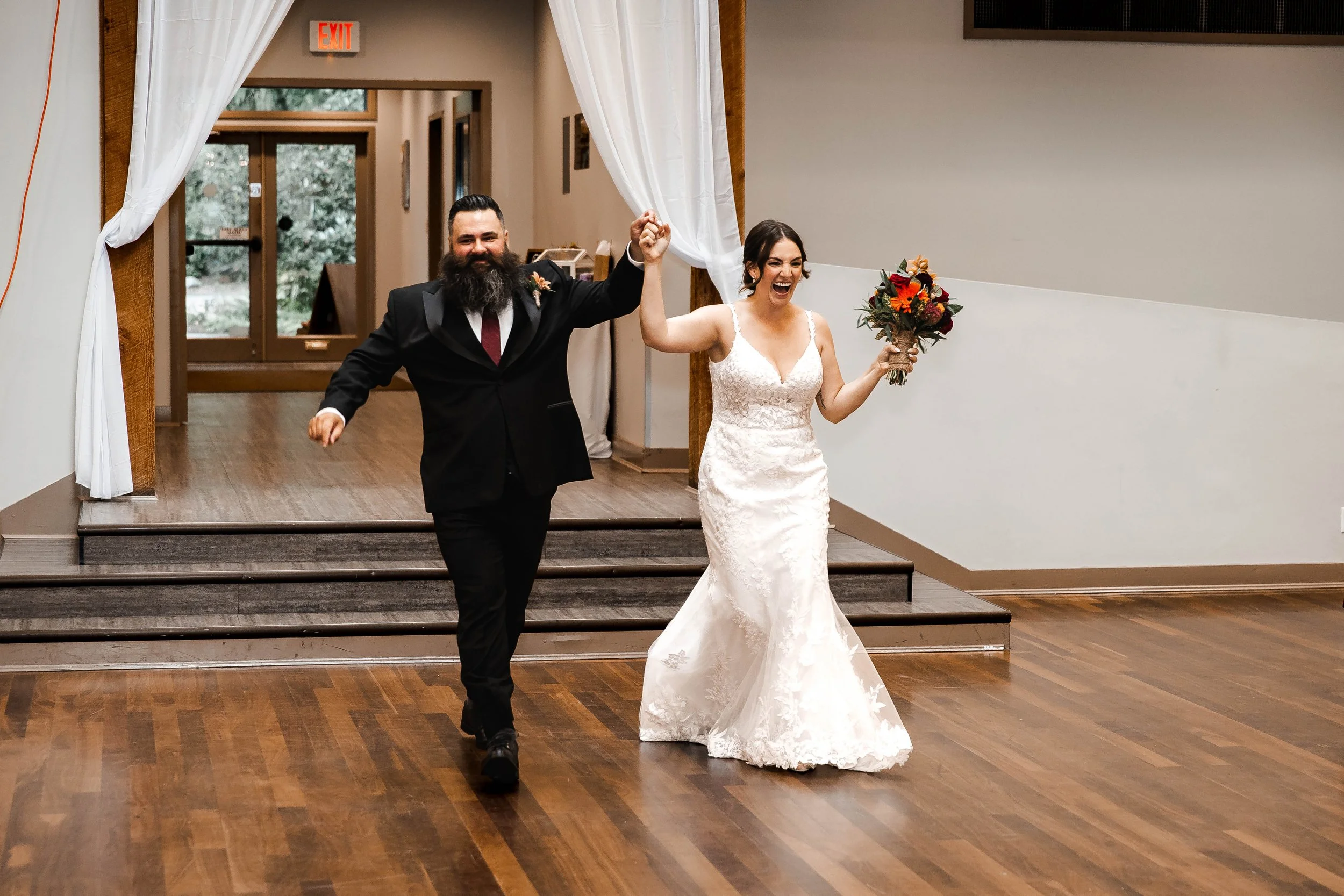 Bride and groom making their joyful grand entrance into their wedding reception, holding hands and celebrating at Whonnock Lake in Maple Ridge, BC.