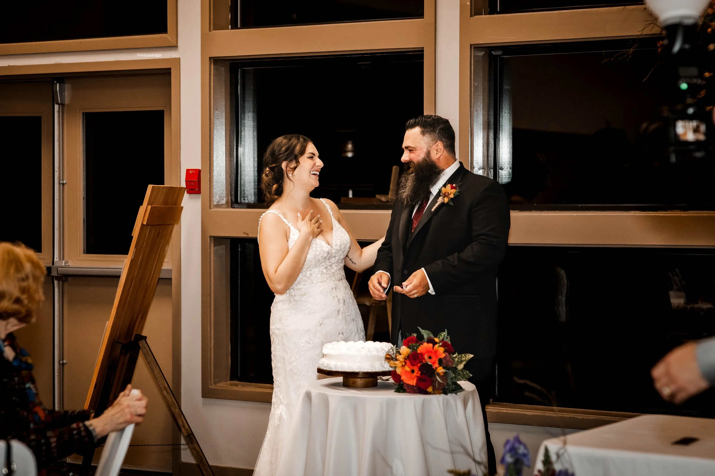 Bride and groom sharing a candid, laughter-filled moment while cutting their wedding cake at their romantic fall wedding reception in Maple Ridge, BC.