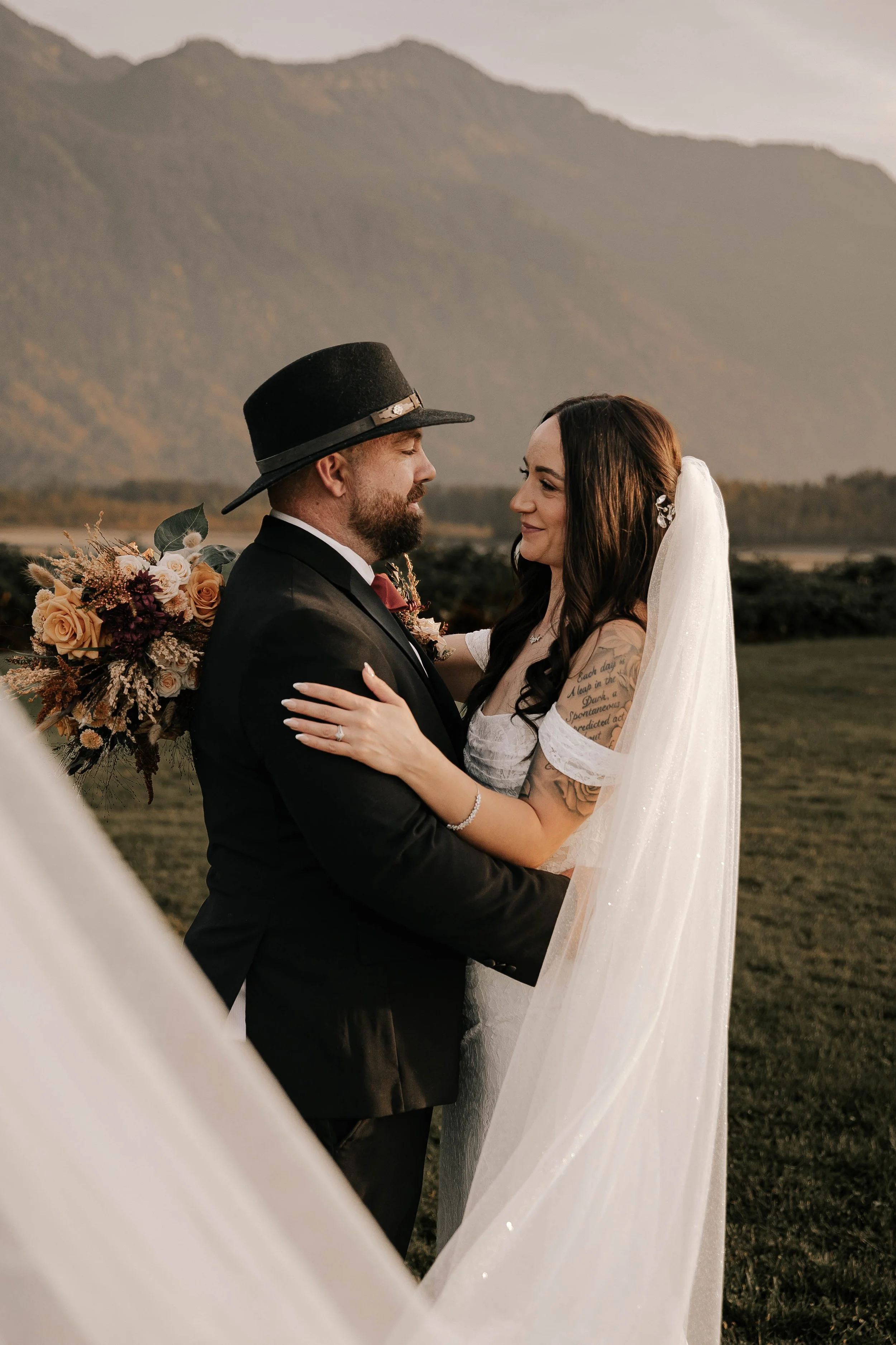 Bride and groom embracing during romantic wedding portraits with mountain views at Fraser River Lodge in Agassiz, BC.
