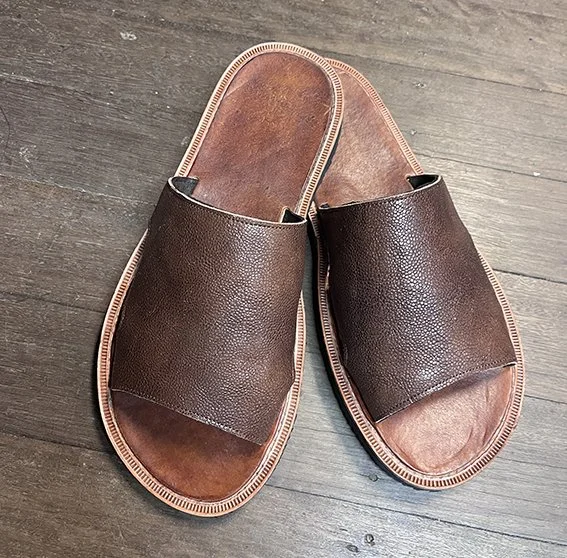 Pair of brown leather slip-on sandals on wooden floor