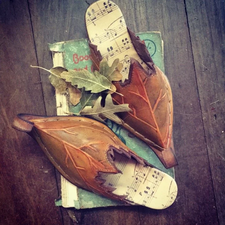 Decorative fall leaves with leather and sheet music on an old book, arranged on a wooden surface.