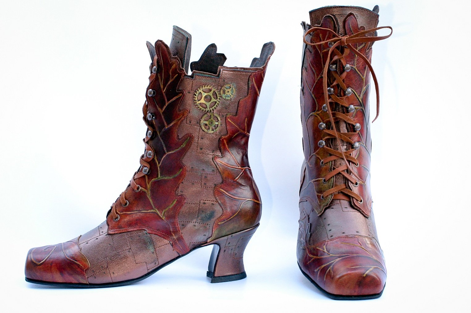 Pair of brown leather ankle boots with stiletto heels, decorated with leaf-shaped leather patches and metallic gear embellishments, against a white background.