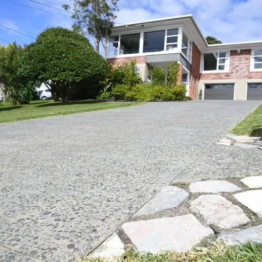 Exposed aggregate driveway with a natural stone edge.