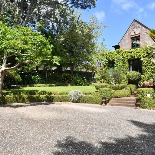 Exposed aggregate driveway framed by mature landscaping.