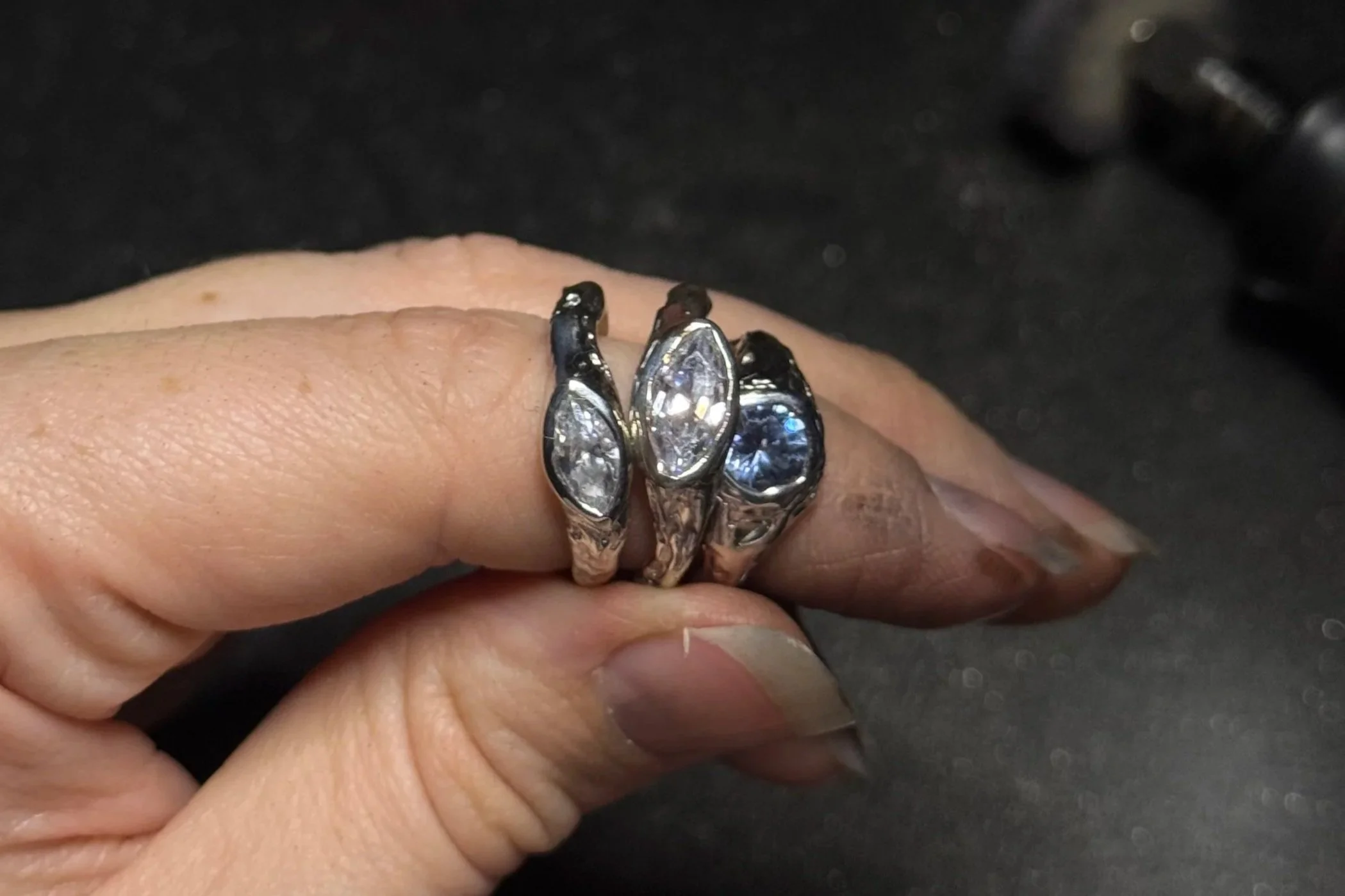 Close-up of a person's hand wearing silver rings with large clear gemstones.