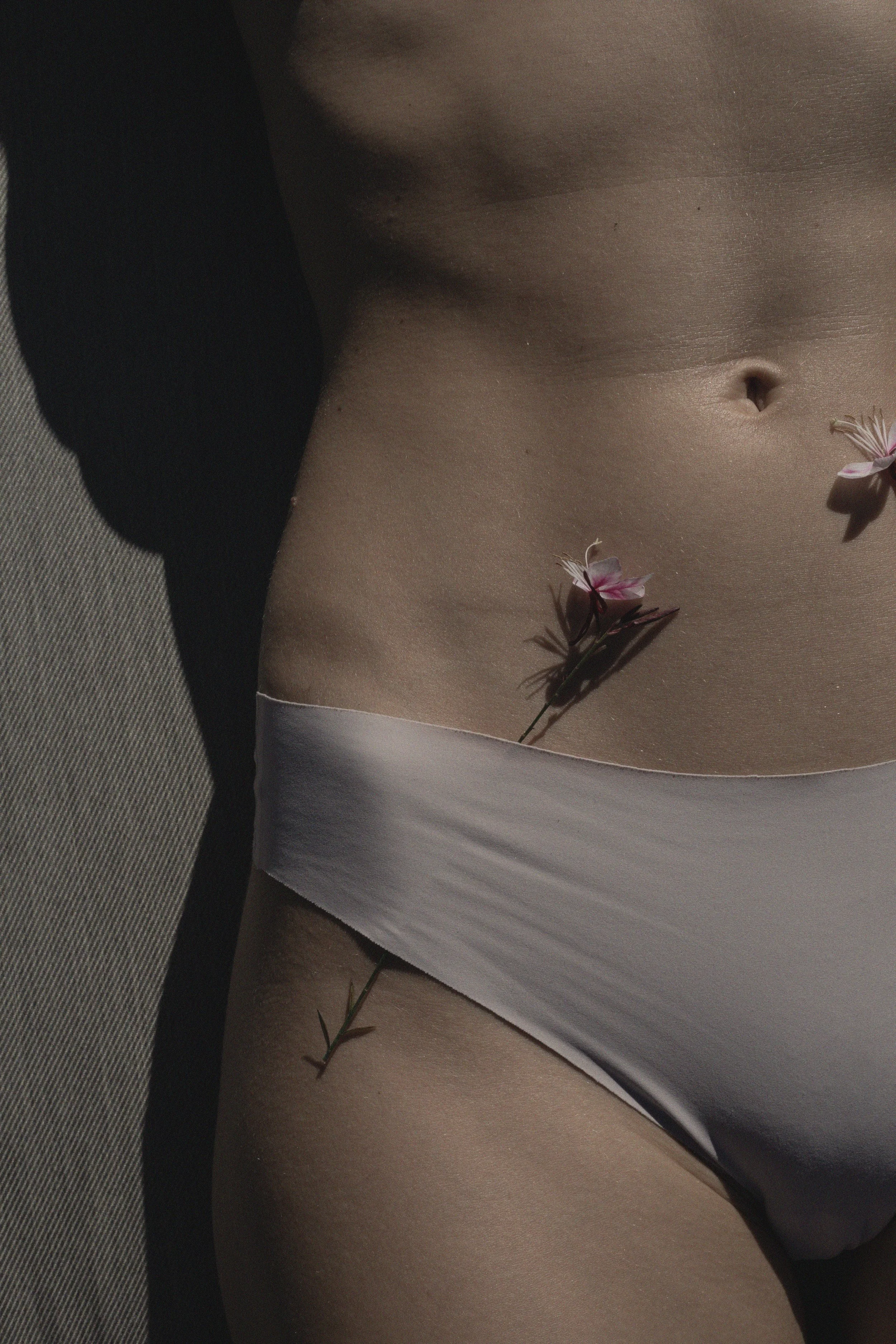 Poitrine d'une personne nue avec des fleurs roses placées sur la peau.
