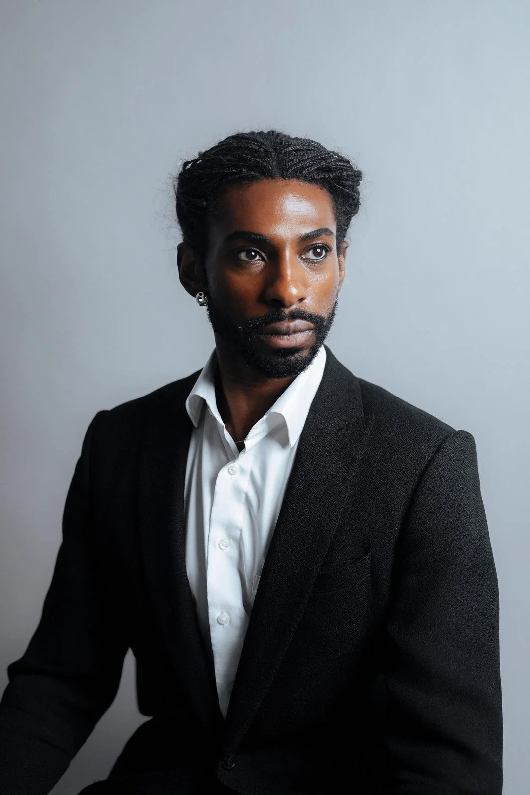 Portrait of Emmanuel Diela Nkita wearing a black suit and white dress shirt.