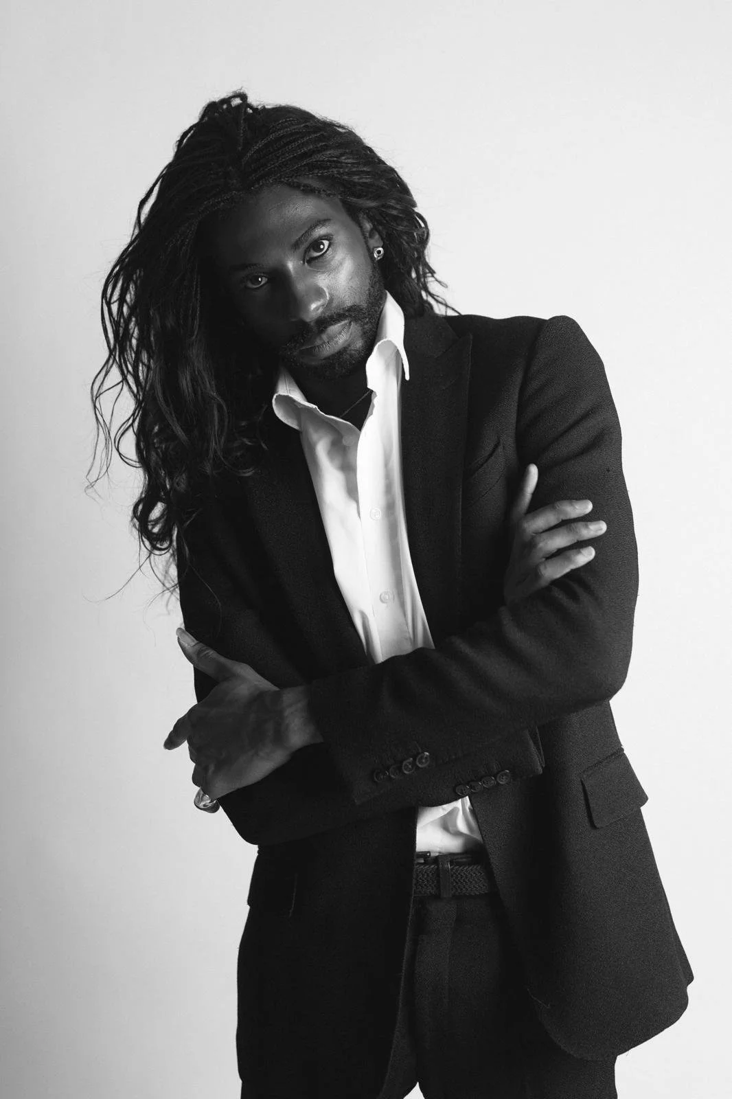Black-and-white portrait of Emmanuel Diela Nkita with long dreadlocks wearing a dark suit and white shirt