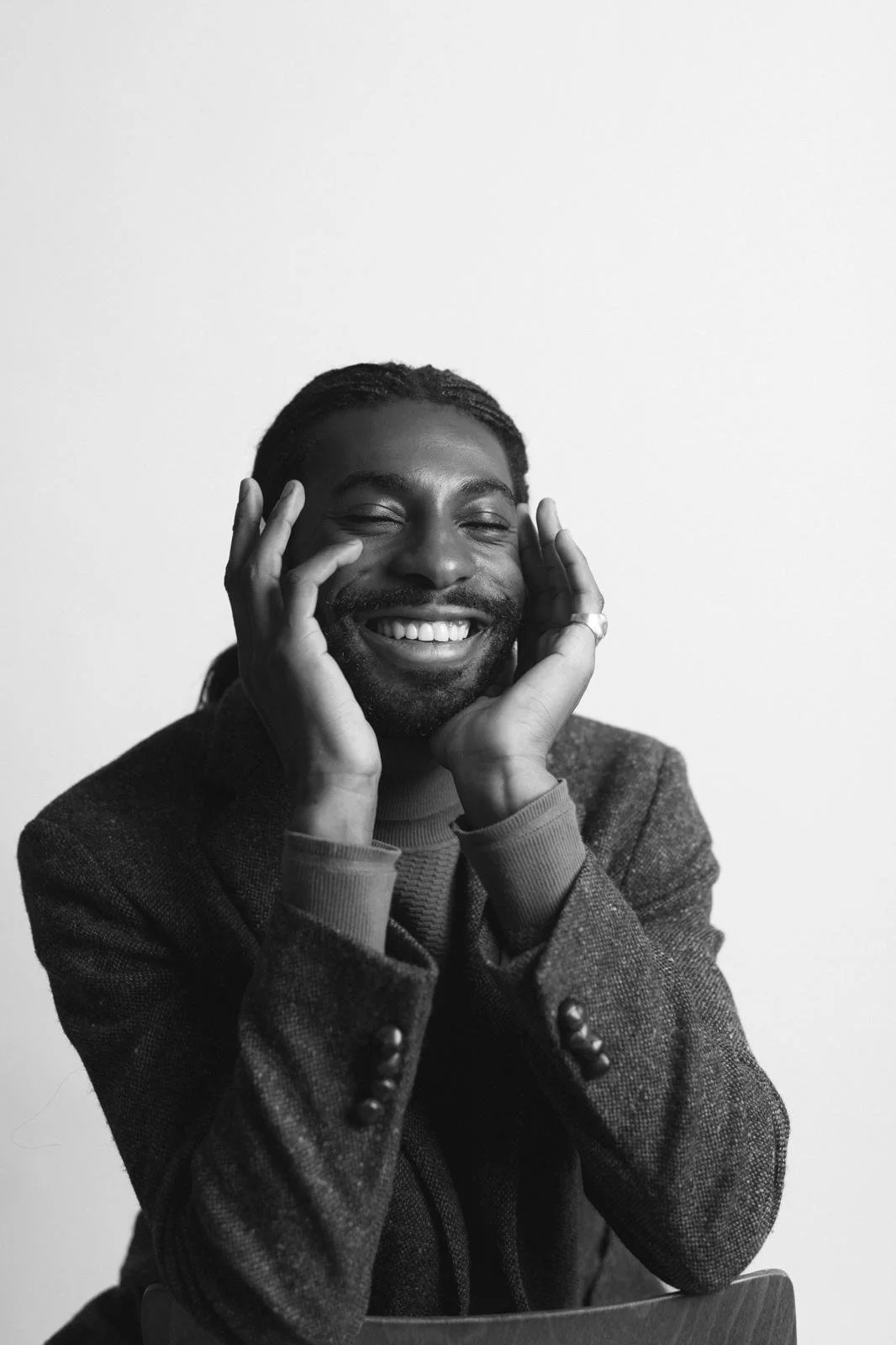 Black-and-white portrait of Emmanuel Diela Nkita resting his face in his hands.